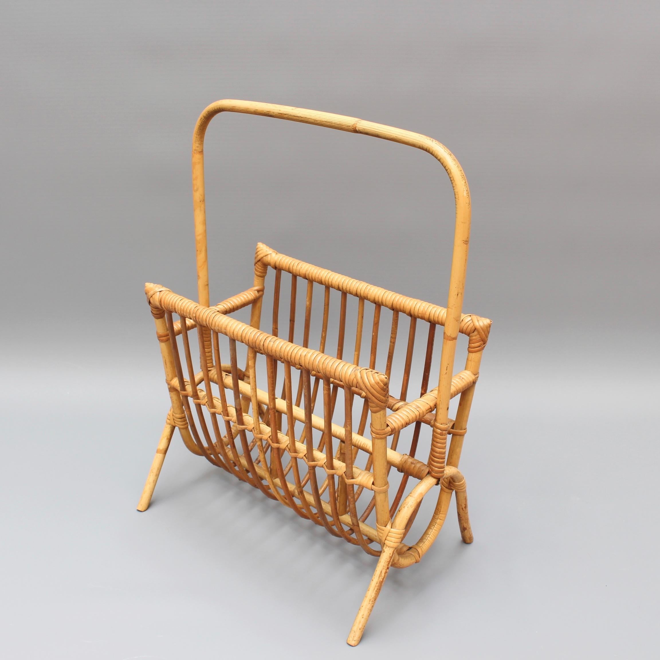 Very sought after French midcentury rattan magazine rack with large handle (circa 1960s). Rattan canes are bound together with rattan strips creating the structure of the rack. Absolutely delightful. In good vintage condition. Commensurate with its