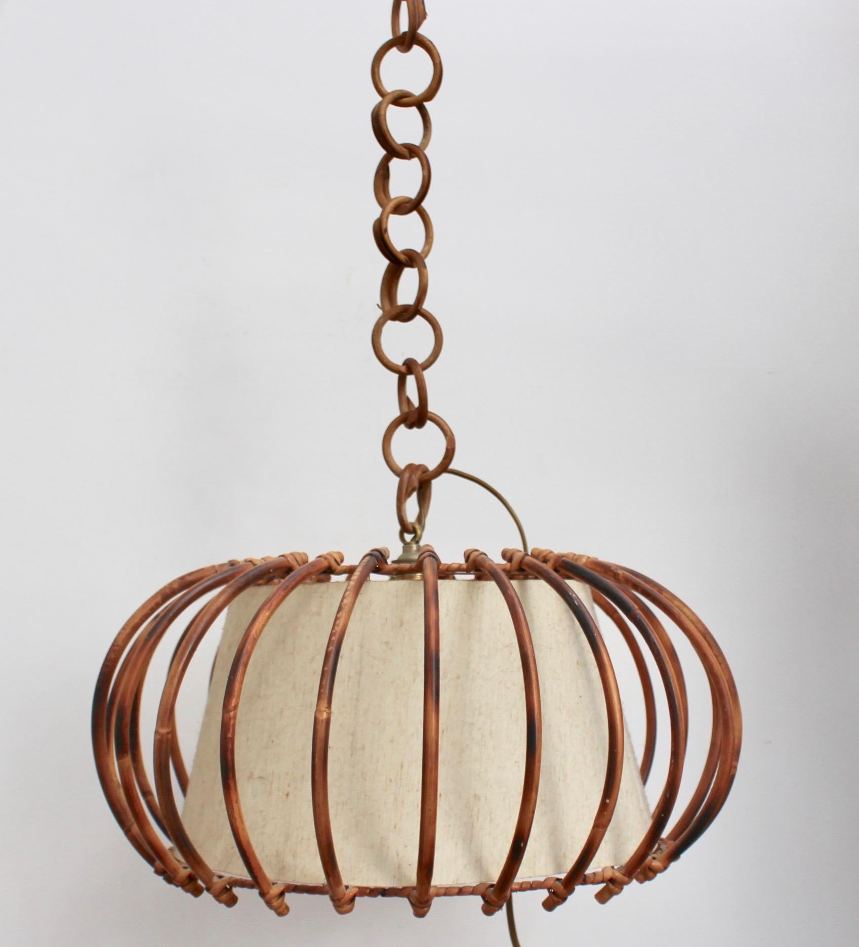 Midcentury French rattan pendant lamp (circa 1960s). Delightfully original, this piece transports you to the French Riviera at the height of its glamour. Hanging with its attached rattan chain, the light fixture consists of a supporting round rattan
