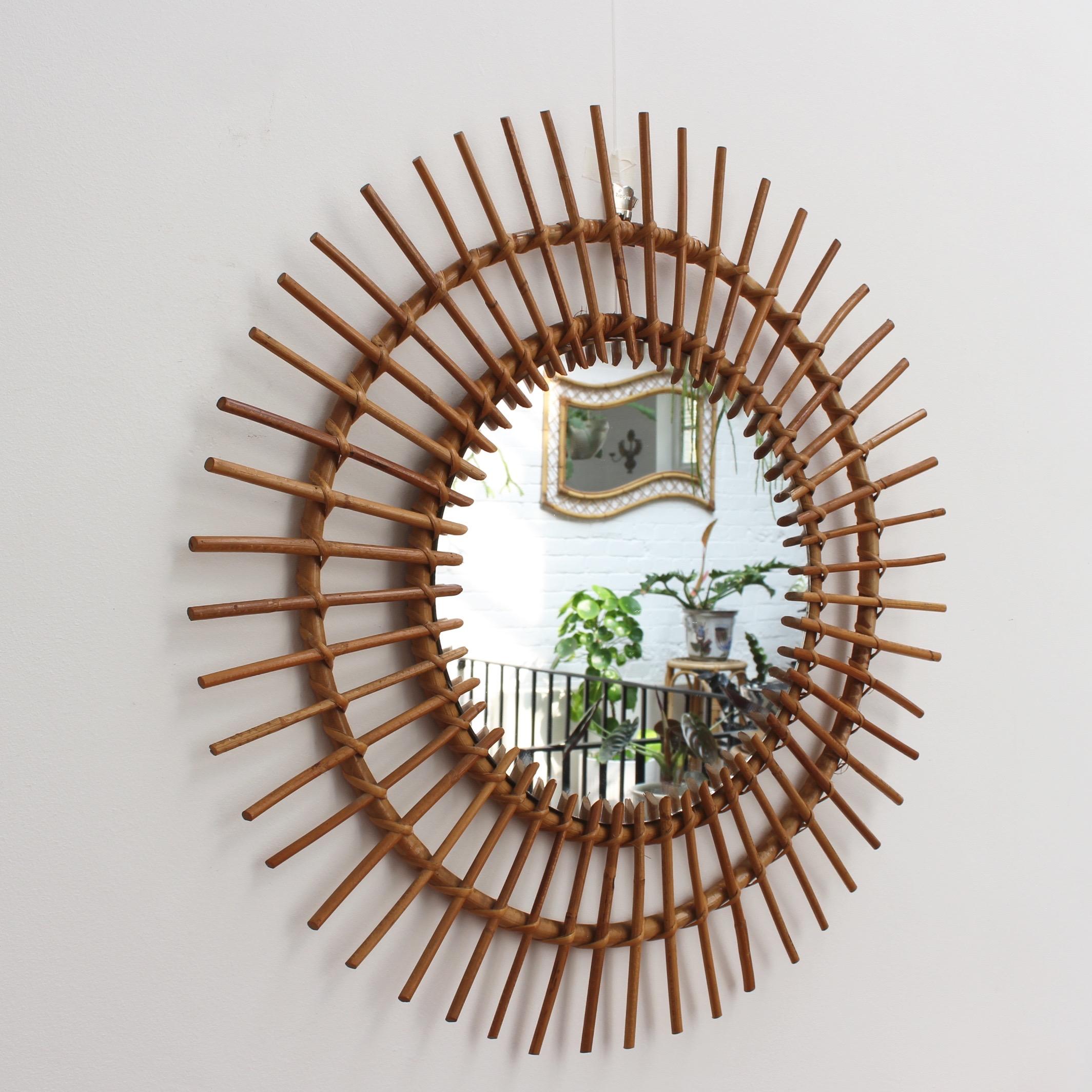 Large midcentury French rattan sunburst mirror (circa 1960s). A vintage collectible classic with sunburst halo and spokes in rattan cane. A designer's favorite, this mirror is in good condition consistent with age and use showing a characterful