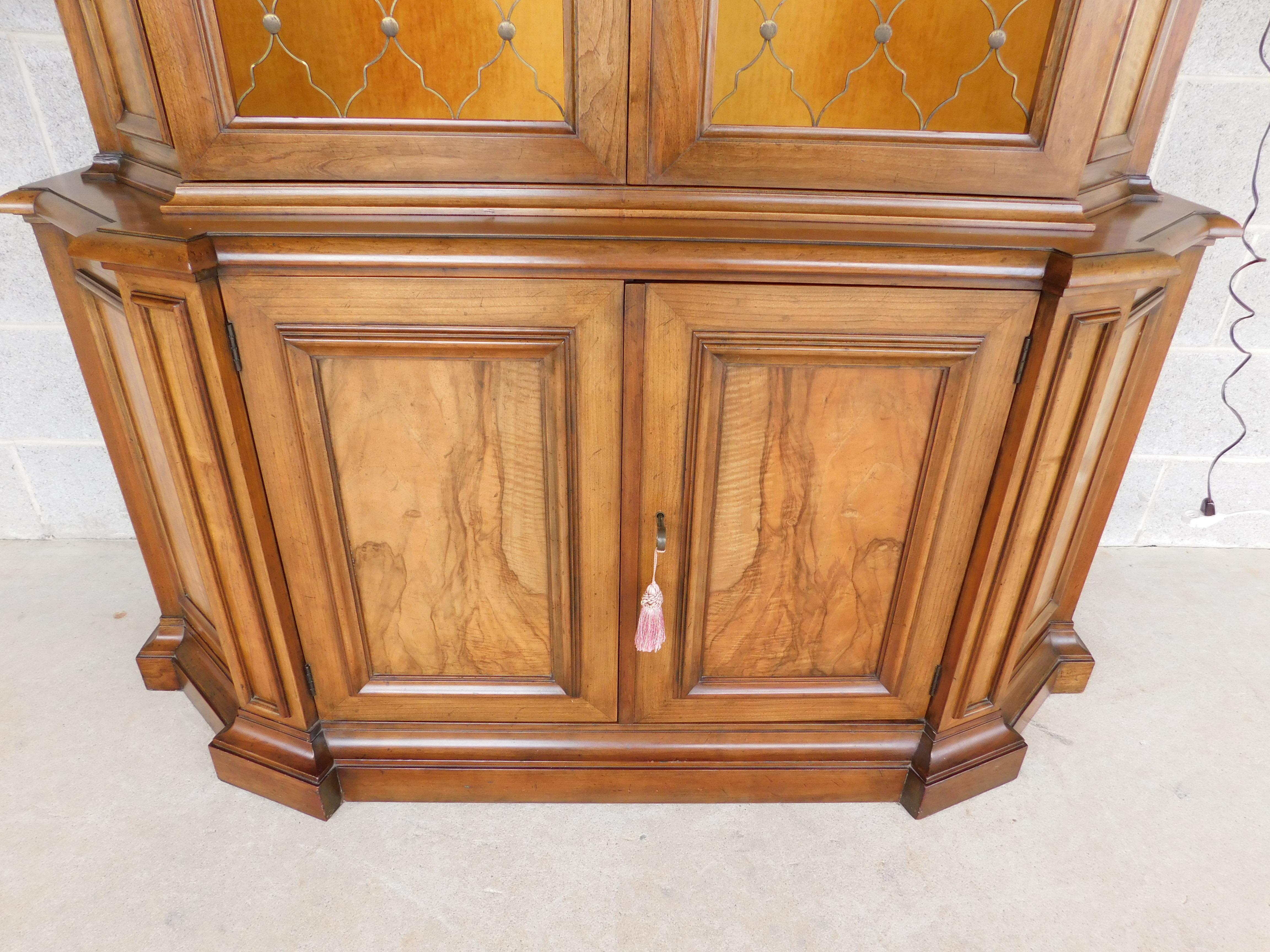 midcentury French Regency Style Baker Furniture lighted 1 piece display cabinet. French and Dutch influence, Arched Top Center Molding. Stepped Columns with Rosewood Accents. Brass Trellis Pattern Doors, inside with Gold Velour Covered Surfaces.