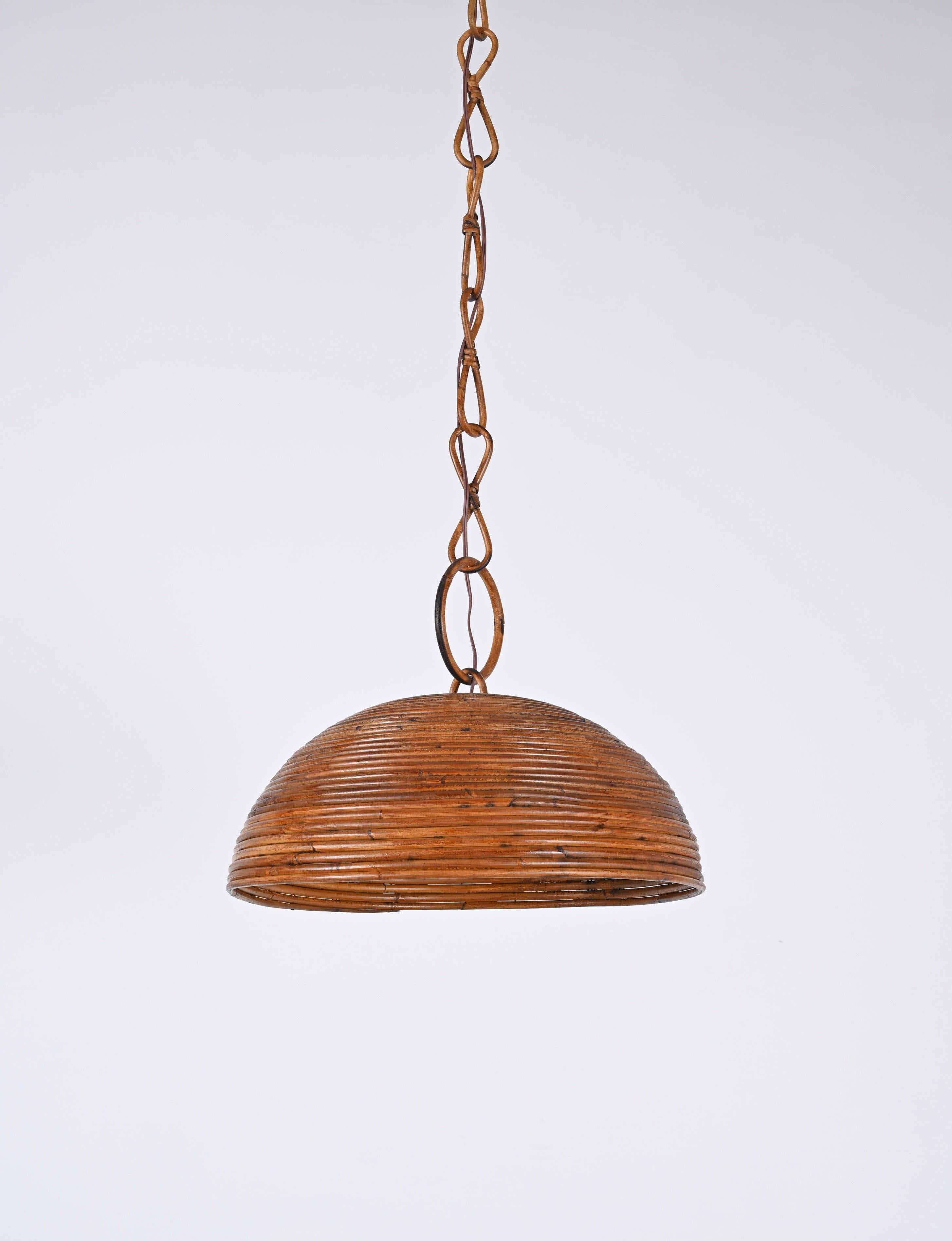 Wonderful midcentury bamboo, rattan circular pendant in French Riviera style, produced in Italy during the 1960s. 
The chandelier consist of a stunning hemispherical shaped lampshade made of curved cane and a chain made of curved bamboo and rattan. 