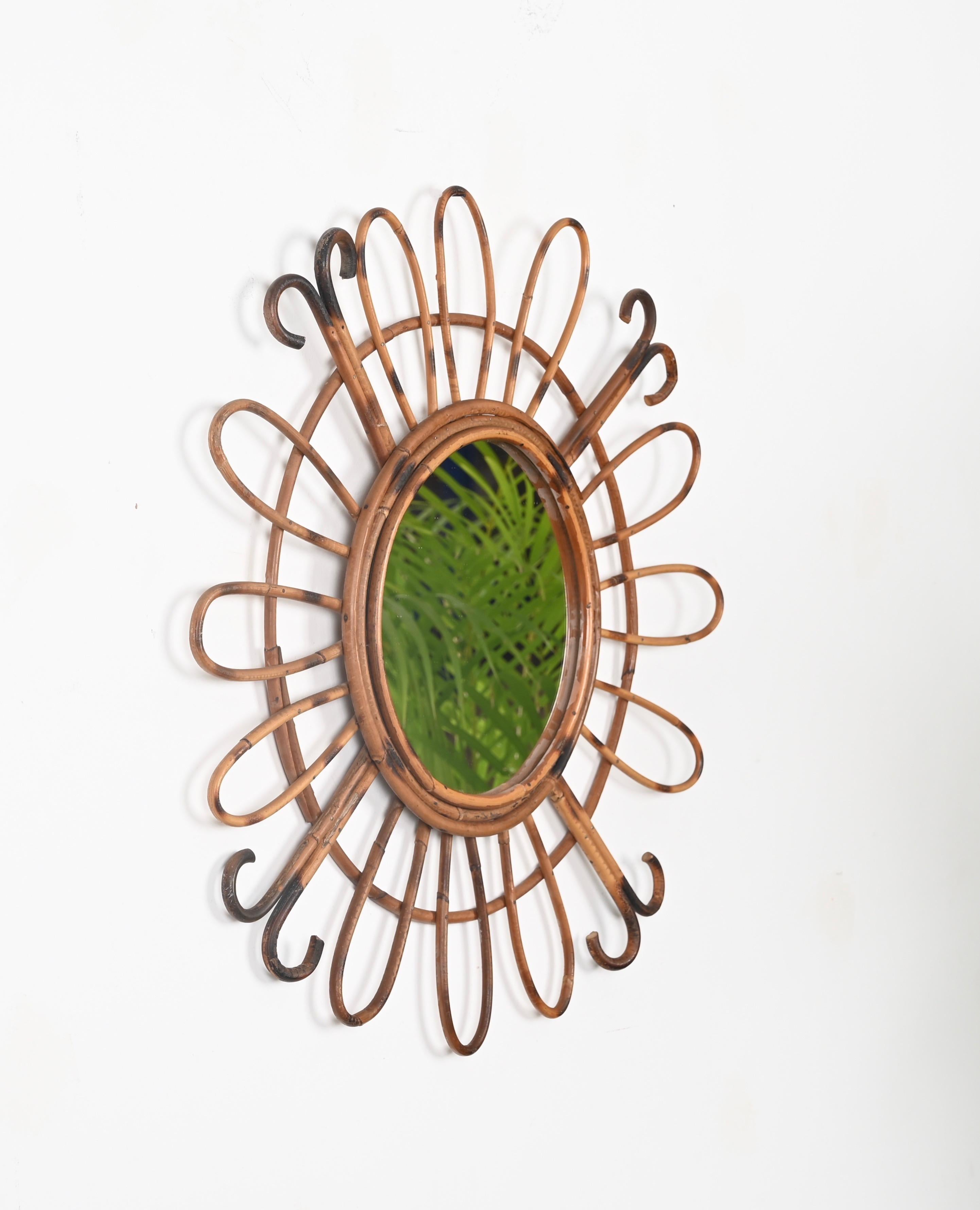 Wonderful Mid-Century French Riviera style sunburst mirror entirely made in curved rattan. This stunning organic mirror was made in France during the 1970s.

This delightful mirror features a round internal frame in fire-curved rattan, decorated