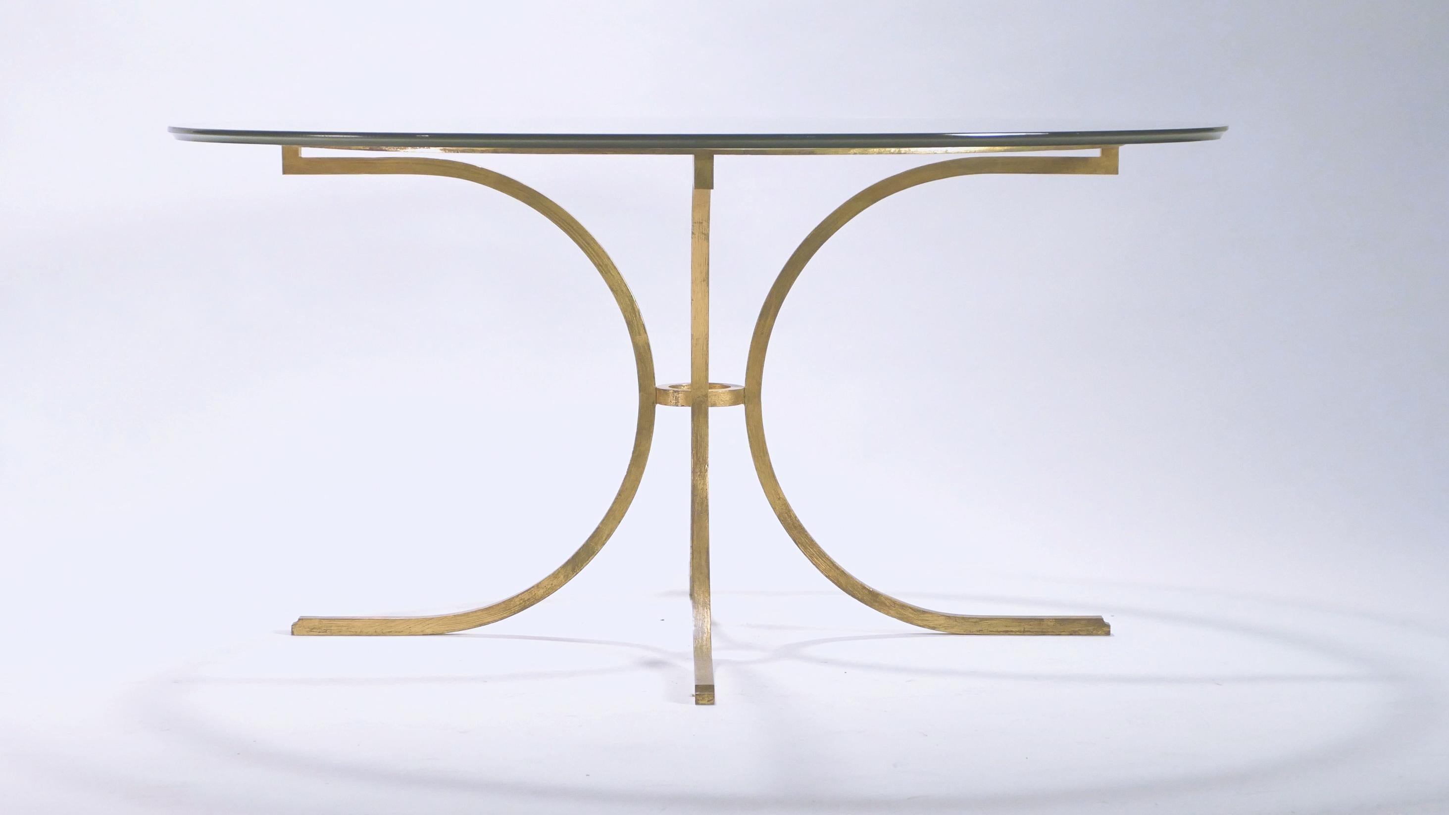 A strategically sparse design with high quality materials gives this rare dining table a sturdy yet delicate appeal. Wrought iron has been gilded with gold leaf for a gentle warm golden patina throughout the entire structure. A thick transparent