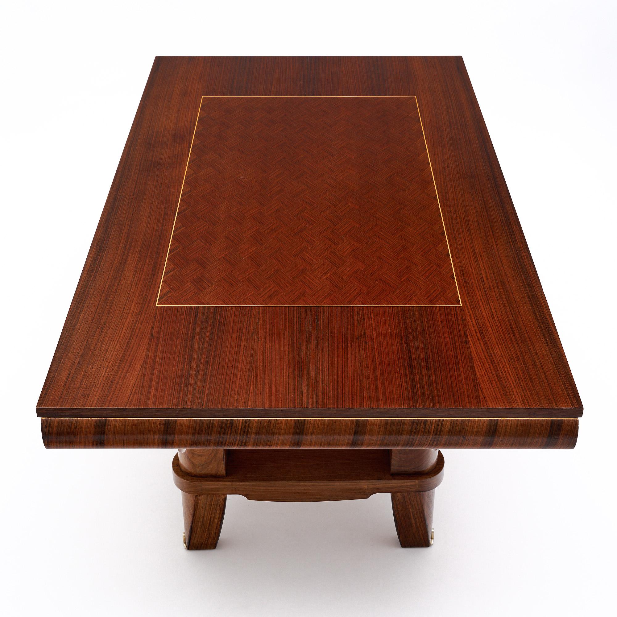 Mesa de comedor de mediados de siglo en Francia, con un precioso tablero de parquet diamantado de palisandro e incrustaciones de madera de limonero. Las patas cónicas y el detalle de los travesaños entre cada una dan a esta mesa un aspecto elegante