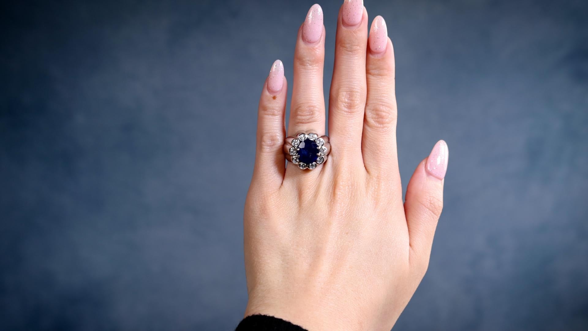 One Mid-Century French Sapphire and Diamond Platinum Ring. Featuring one oval mixed cut sapphire of 5.10 carats. Accented by ten transitional cut diamonds with a total weight of approximately 0.70 carat, graded F-G color, VS-SI clarity. Crafted in