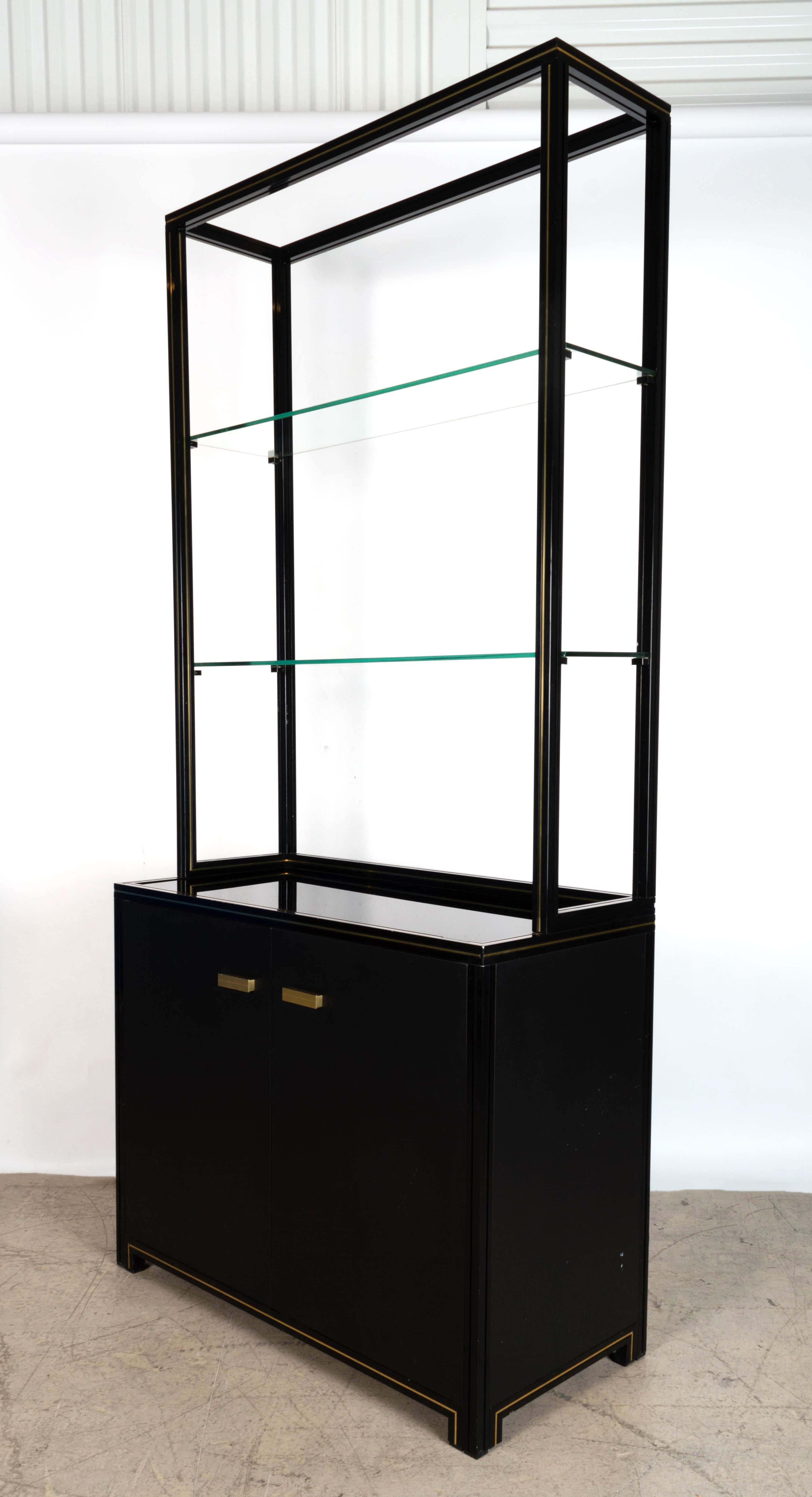 Mid century French shelving display cabinet bookcase C.1970.

PIERRE VANDEL, PARIS: A black and gilt lacquered display cabinet, the frame form superstructure with two glass inset shelves, above an inset black shelf top, with cupboard doors,