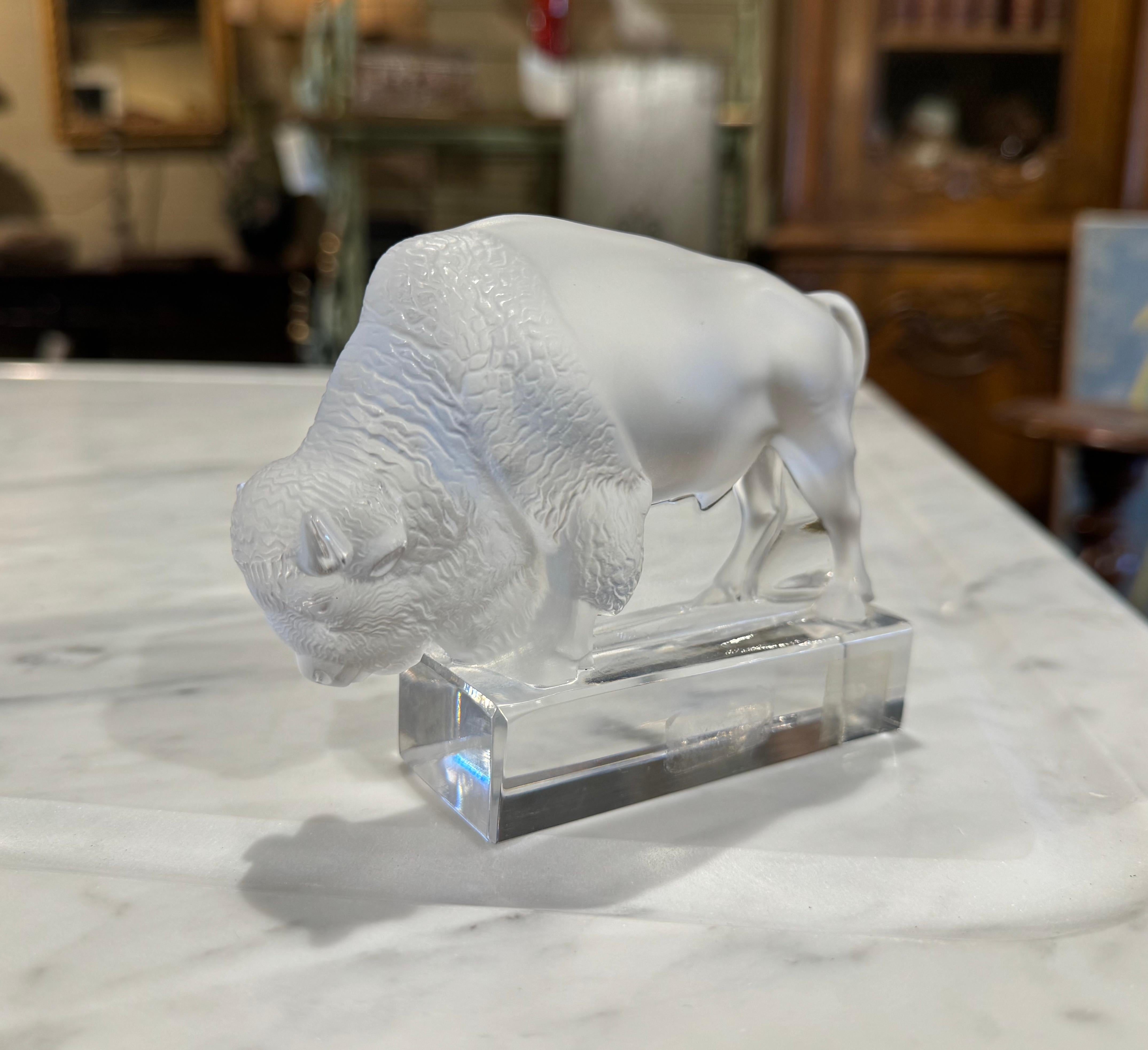 Decorate a shelf or a desk with this fine bison sculpture. Created in France by Lalique circa 1970, the frosted crystal bird is signed on the base. The paperweight bovin sculpture is in excellent condition with rich colors. Etched signature Lalique