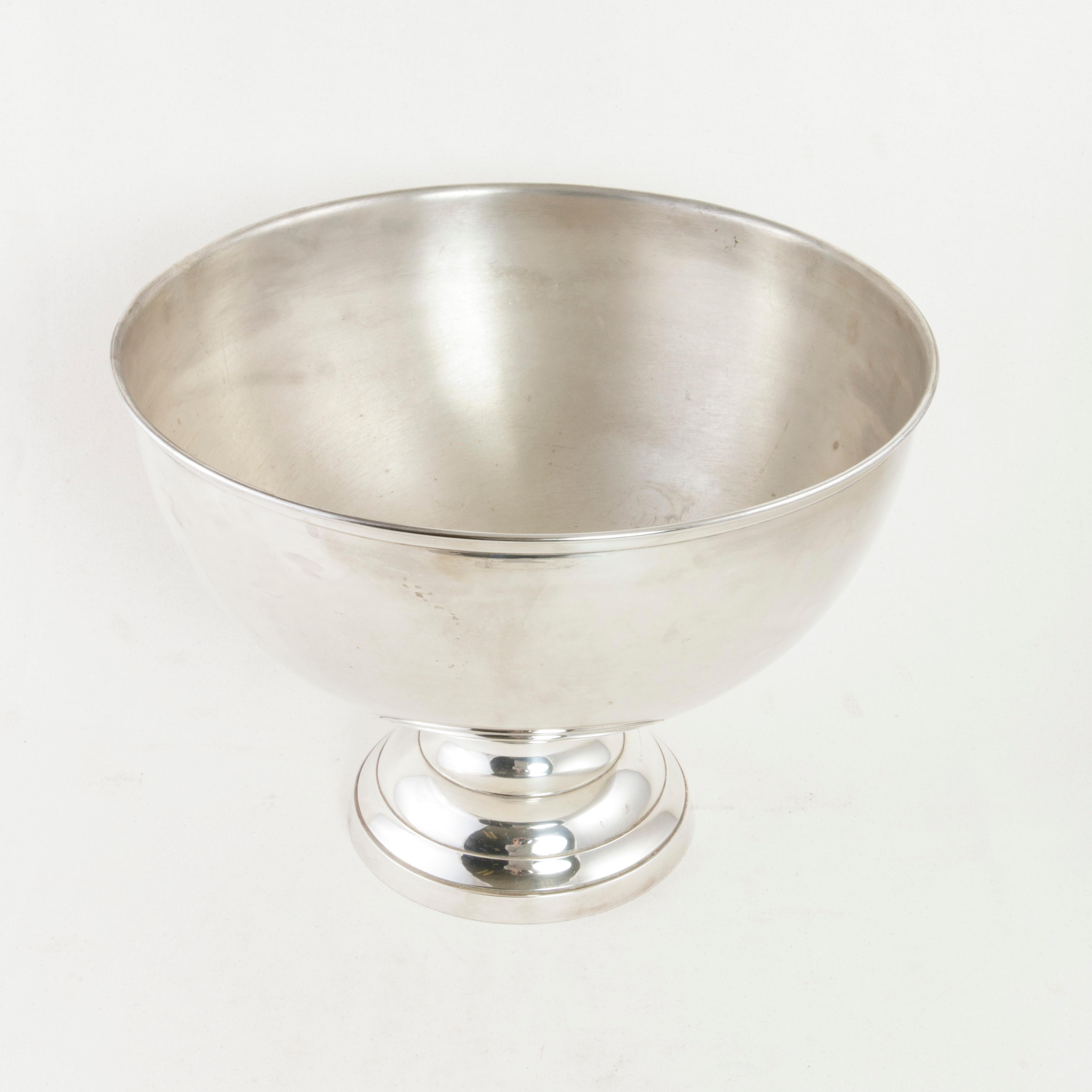 This midcentury French silver plate hotel champagne bucket features a 15.5 inch diameter bowl that rests on a footed base. The base is stamped with the silver plate hallmark. A removable insert with twelve points rests on the rim and is used to