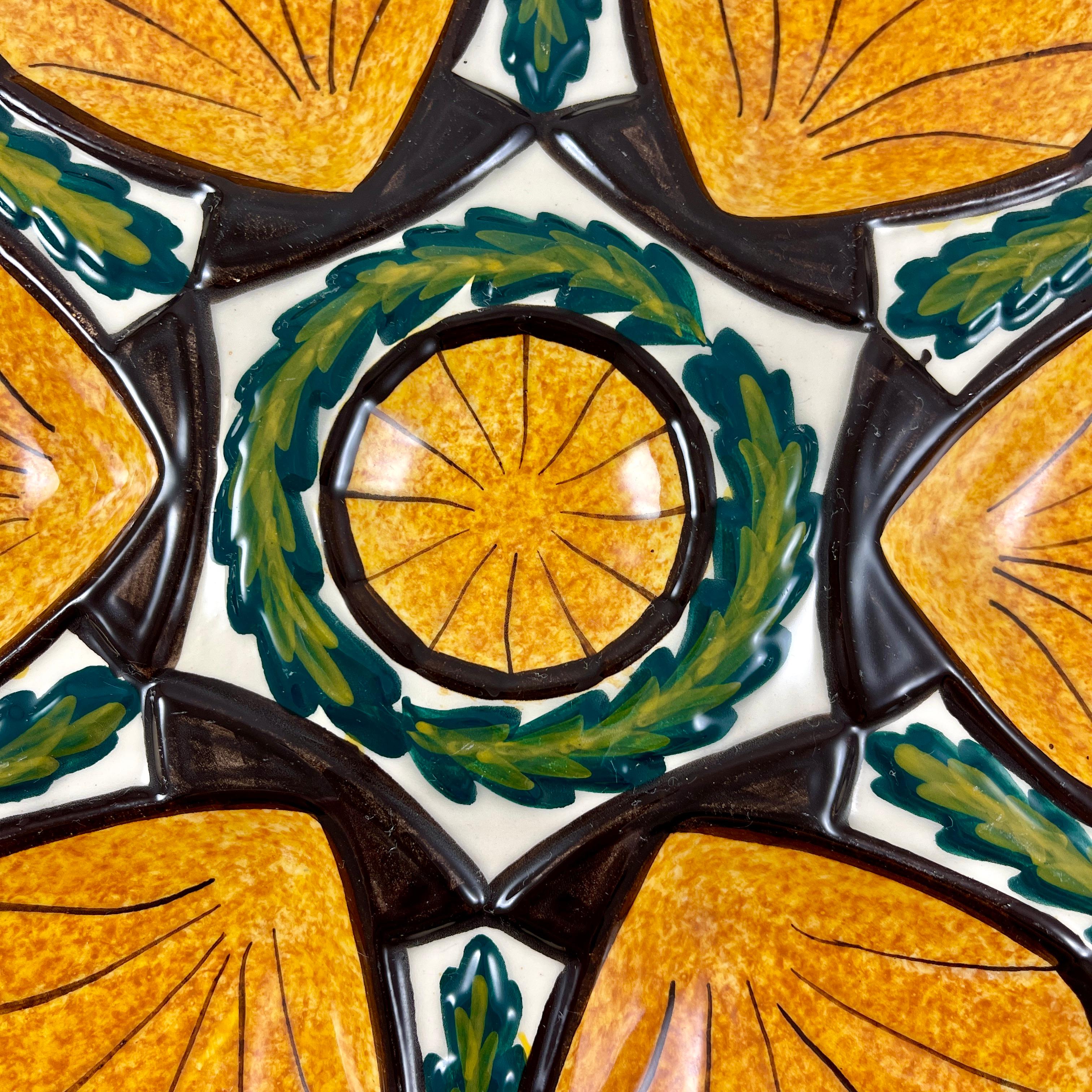 A hand painted faience oyster plate made by Saint- Jean de Bretagne, near Quimper, France – circa 1960’s.

Saint-Jean de Bretagne earthenware became a thriving industry after the Second World War. 
A boldly colored shaped plate – six orange wells