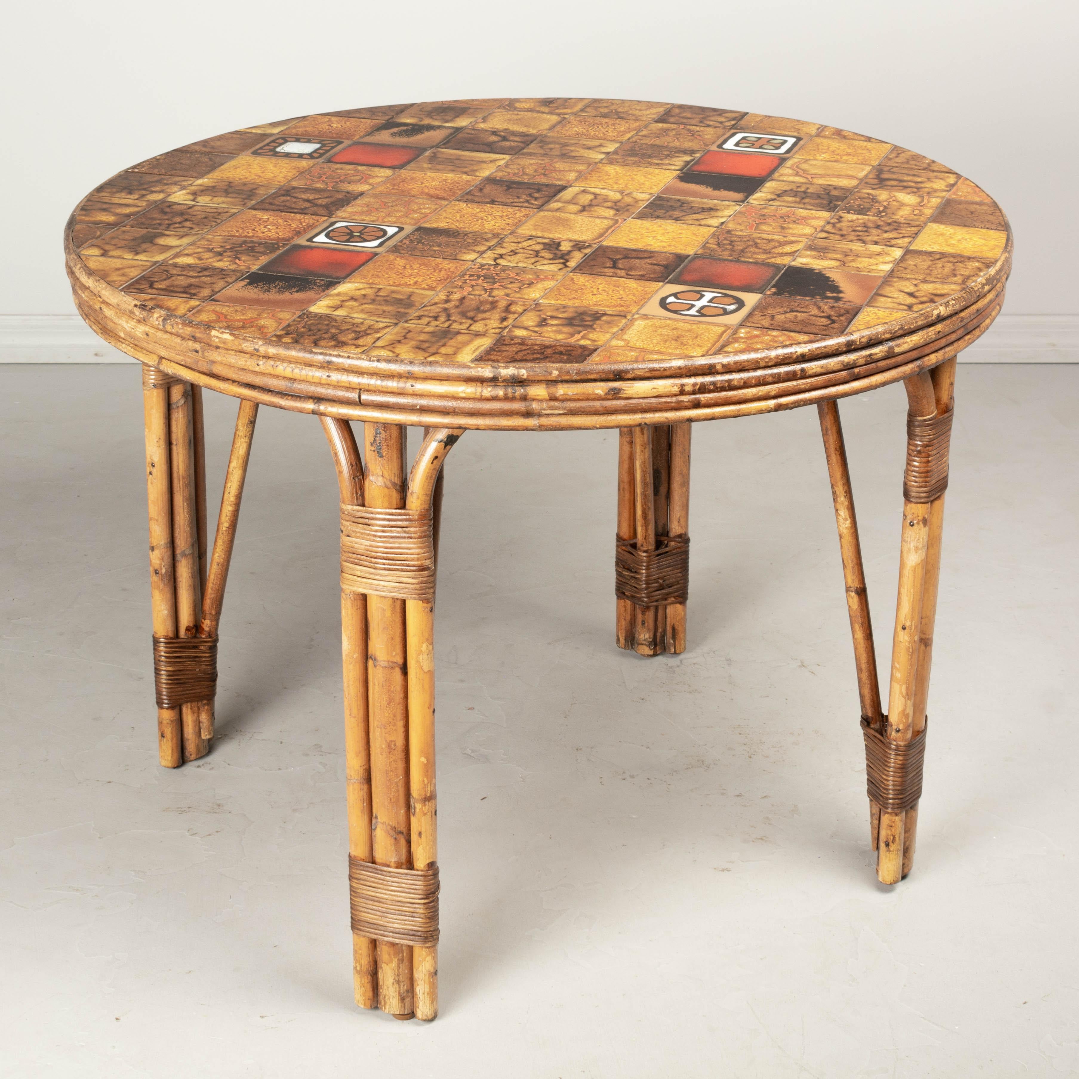 A vintage French Vallauris pottery tile top table with sturdy rattan base. Each glazed ceramic tile is unique and laid out in a random mosaic design. Mid century style typical in the South of France and the French Riviera. In good condition with