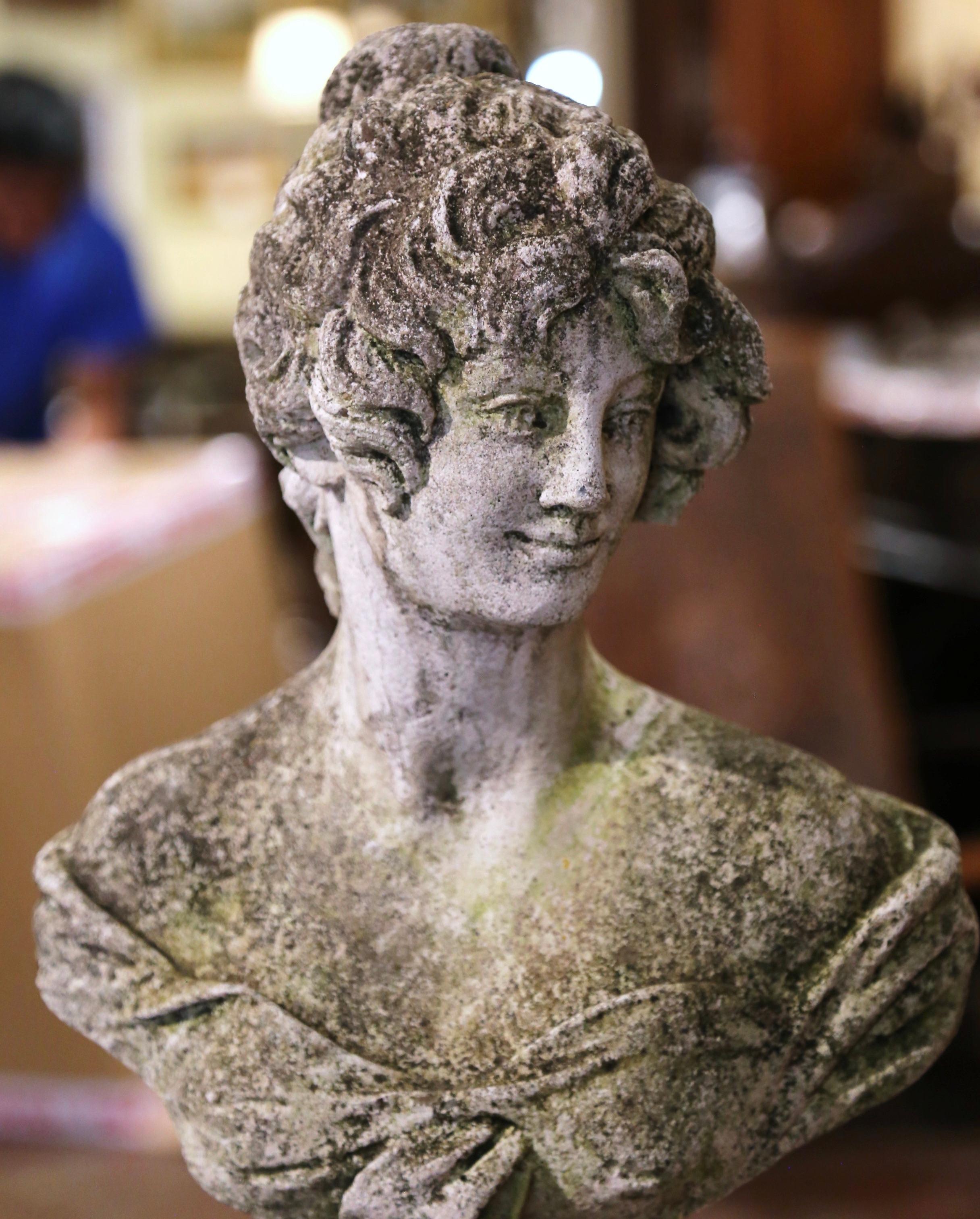 Decorate a garden or patio with this elegant antique outdoor statue. Carved of stone in France circa 1960, the figure stands on a flared square base and depicts a young woman bust, her head turned; she has long hair arranged in a top knot, and is