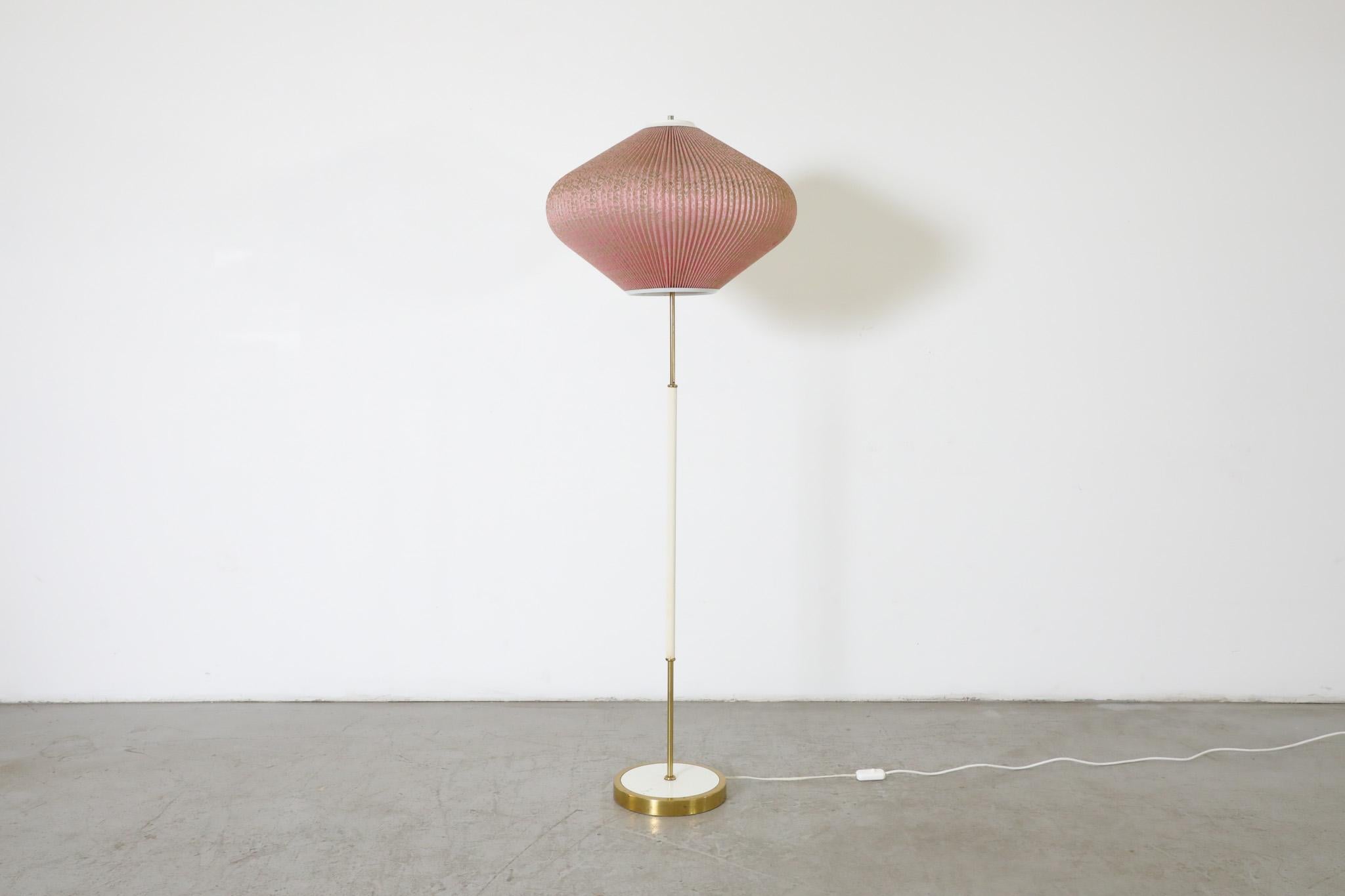 Mid-Century, 1960s Rispal inspired white enameled metal and brass floor lamp with pink pleated lace lampshade. The lampshade is a lace infused pleated plastic and in good original condition. The stem and base have visible wear, including scratching,