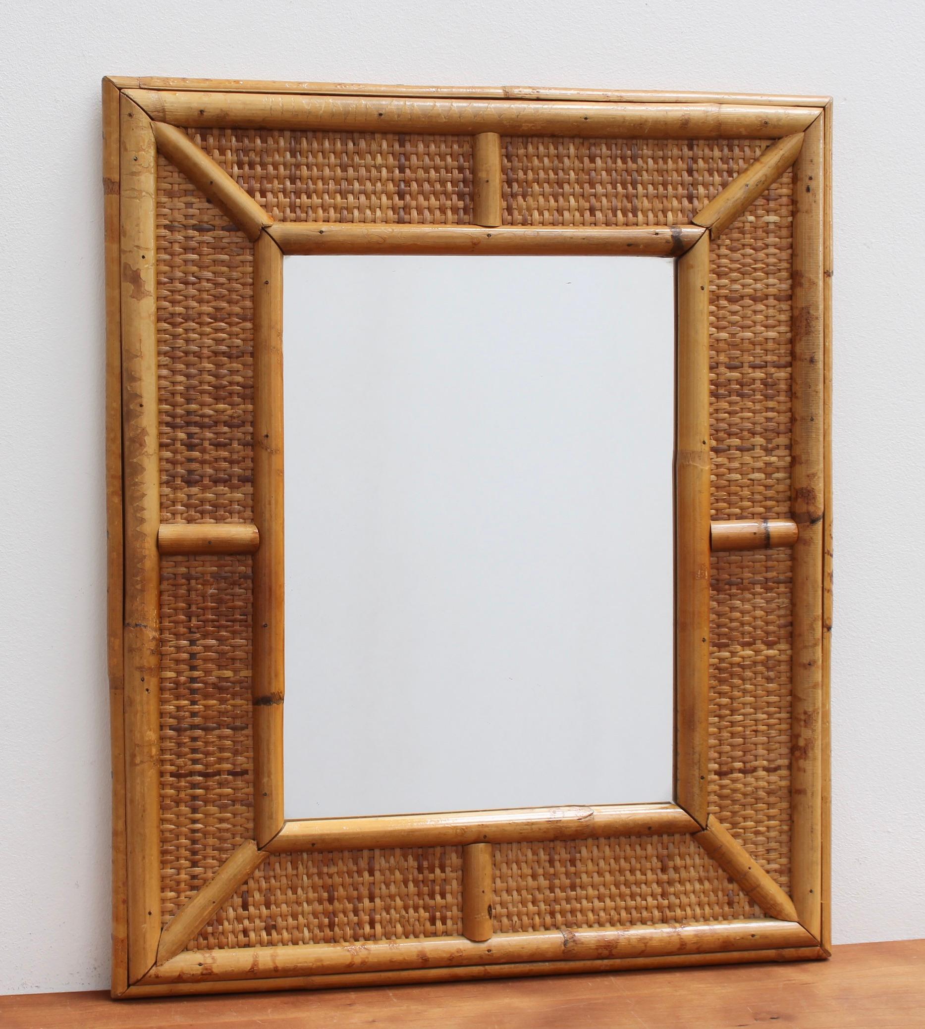 Mid-century French wicker and rattan wall mirror, (circa 1960s). This mirror has a delightful rectangular shape with glass enclosed by the caned frame which is itself, framed by wicker and more cane. The wicker In between the two frames is