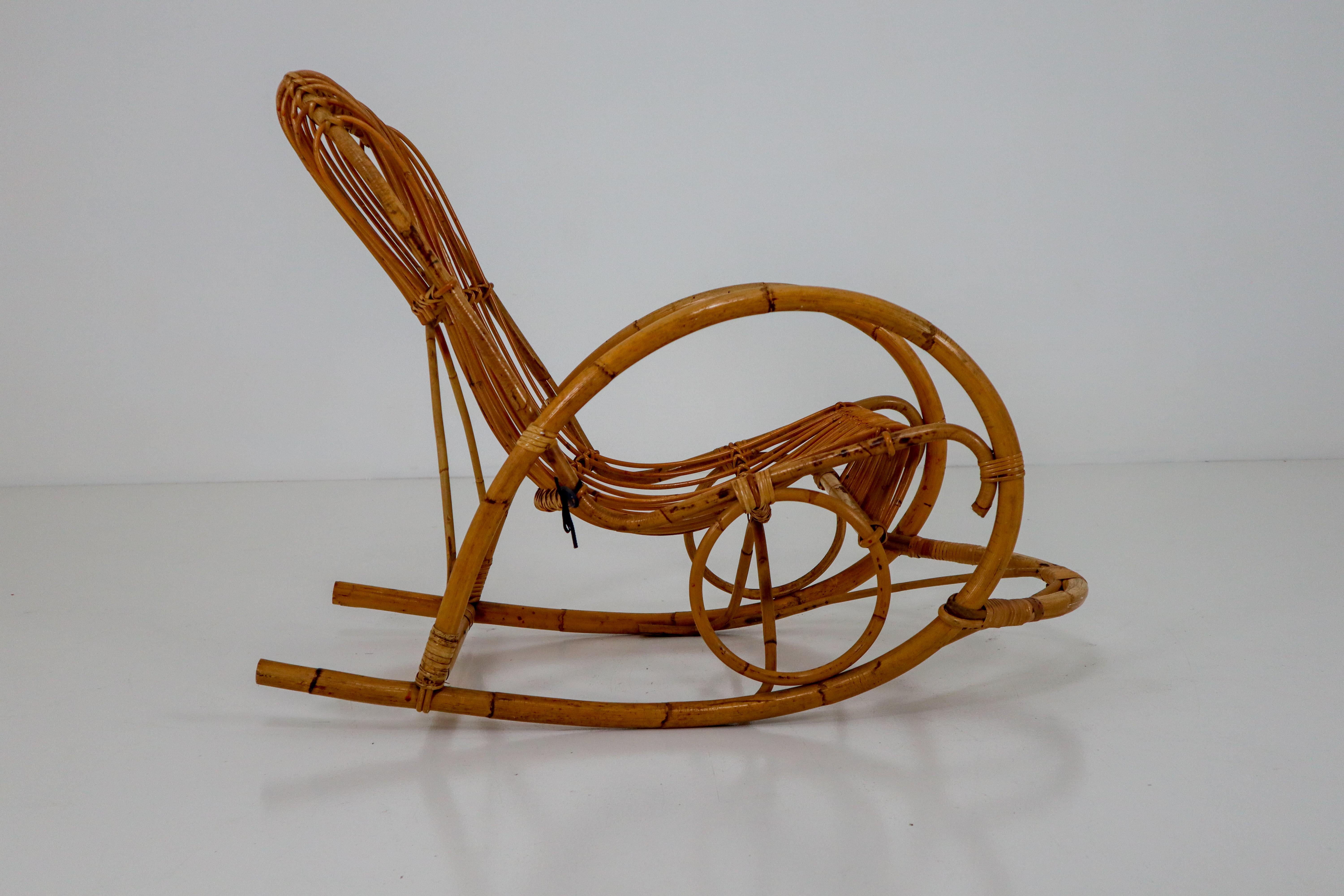 Midcentury French arm rattan rocking chair and features a steam bent bamboo frame. This rare rocking chair was made in the late 1960s .Great curves and good original condition.