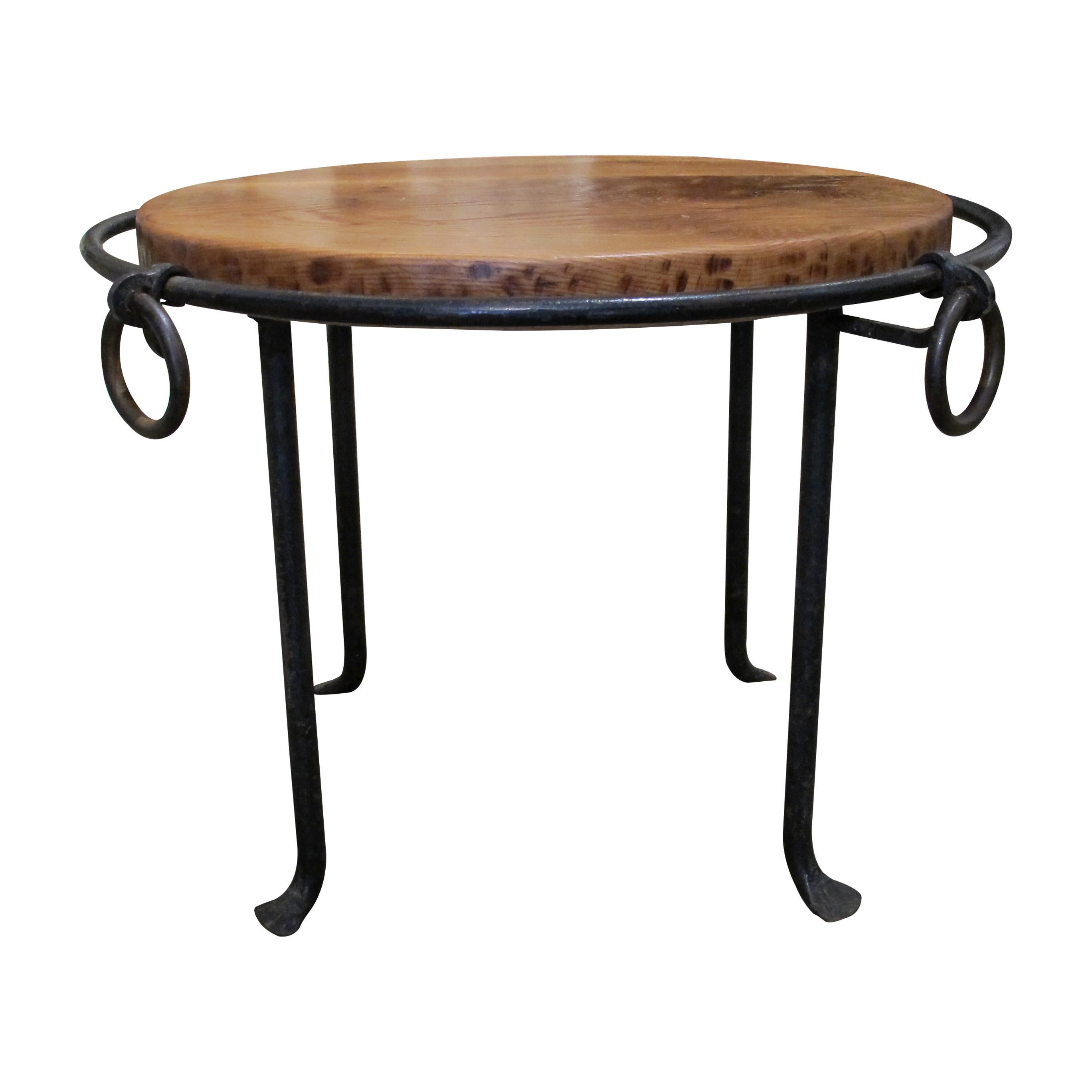 A mid-century French coffee table with a solid oak top and a sturdy wrought iron base. The circular design features simple hand-forged details, including ring accents and slightly curved legs. The warm oak surface complements the dark iron frame