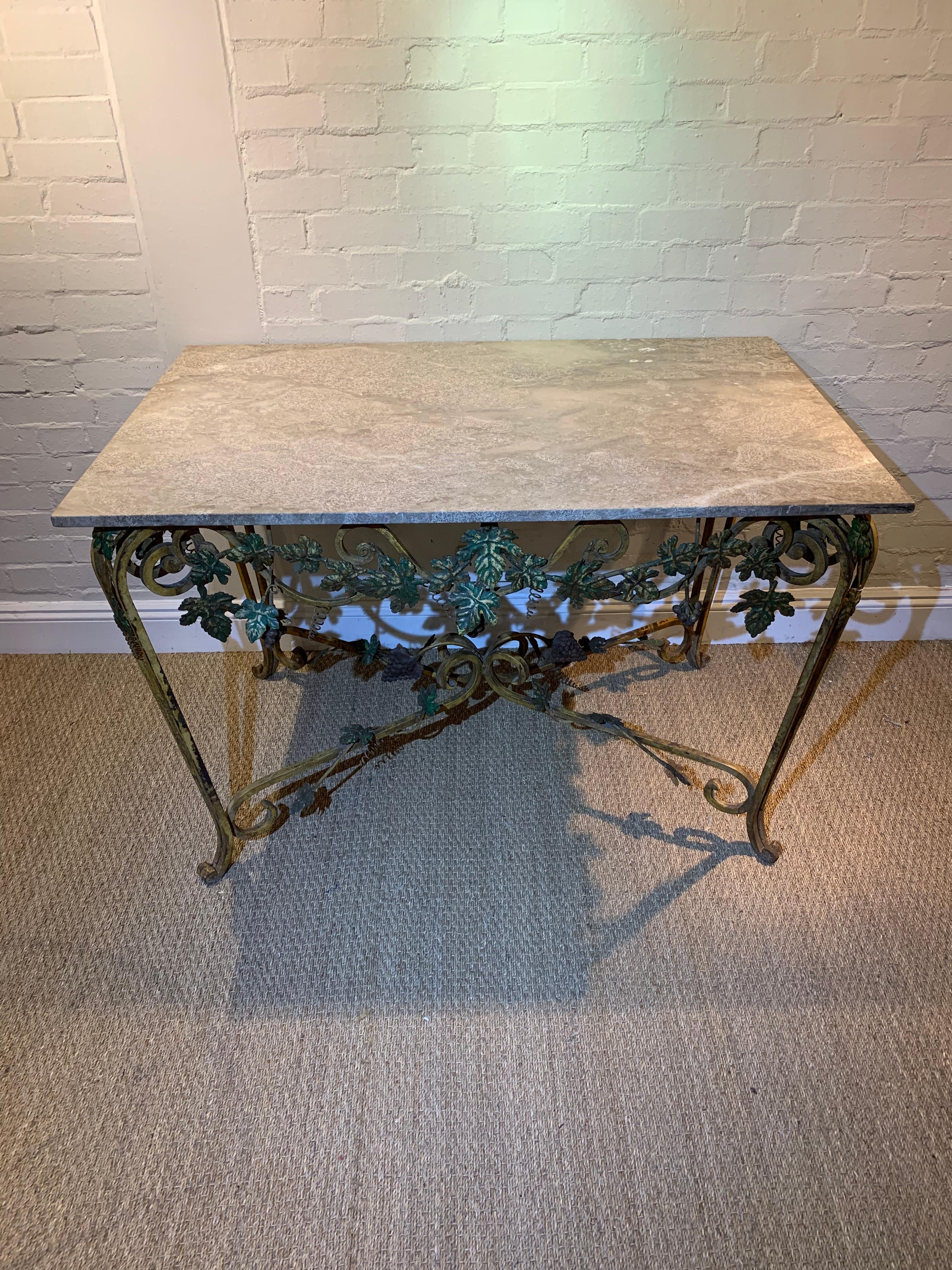 Midcentury 1950s painted and gilded French rectangular wrought iron console table featuring scroledl legs, decorative trailing leaves across the front and also in the centre.
The marble which has likely to have been replaced is a neutral pale beige