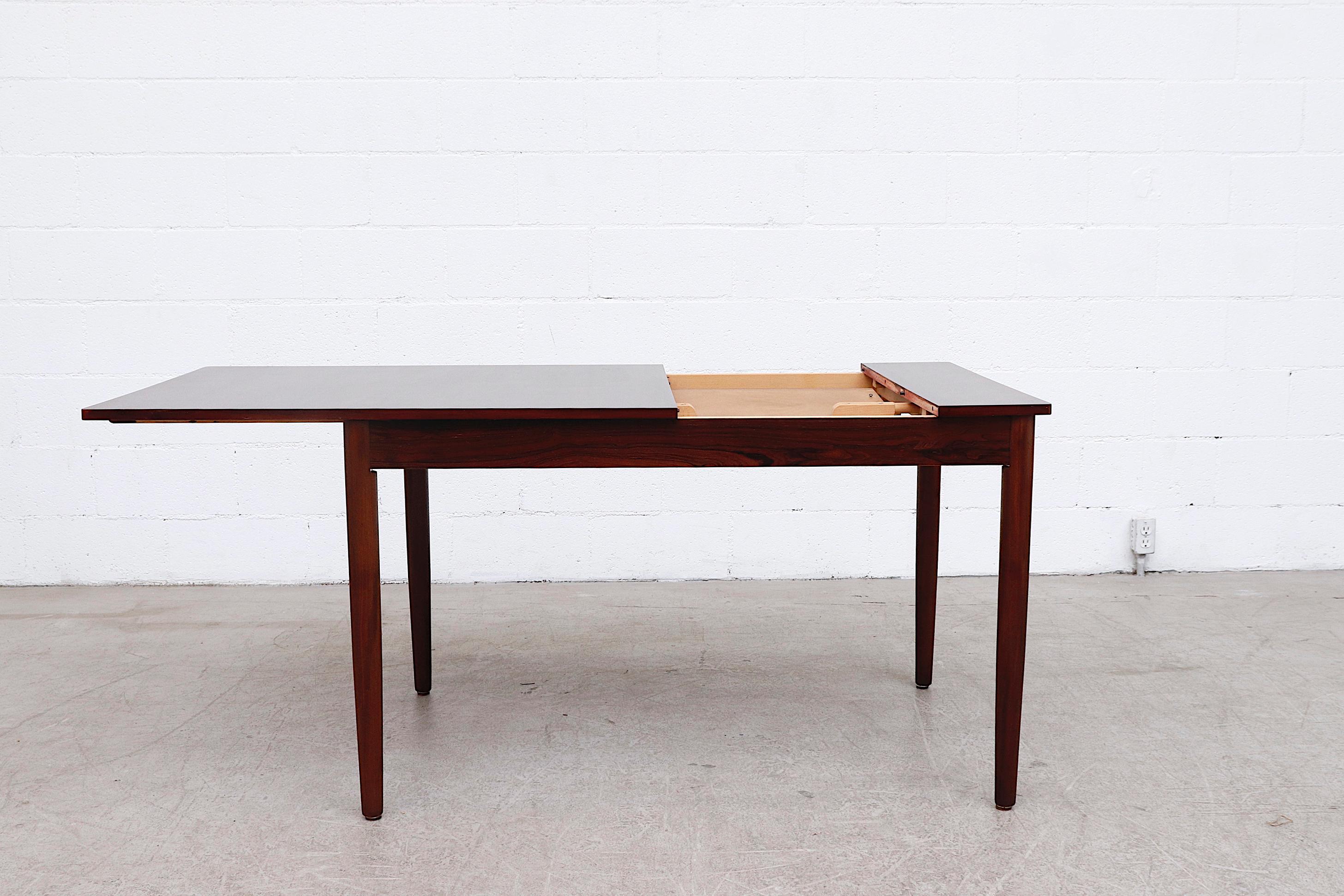 Gorgeous mid-century Fristho rosewood dining table with hidden leaf. The table measures 66.75