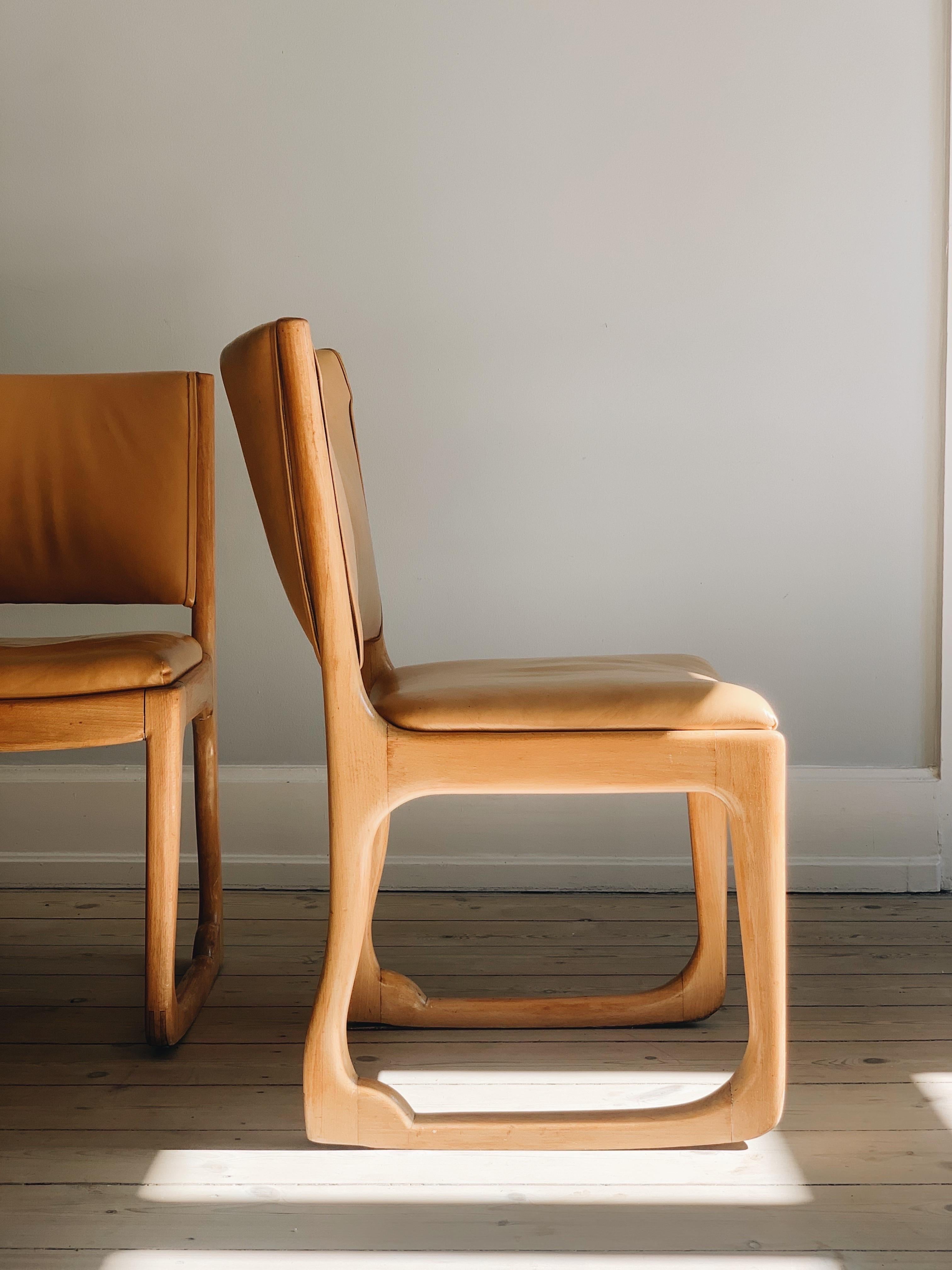 Designed in 1949 by Holger Jacobsen, and manufactured by Fritz Hansen. One chair with a Fritz Hansen label to the underside. Each with a stained beech frame with upholstered back and seat. The front and back legs joined by bowed glides allowing the