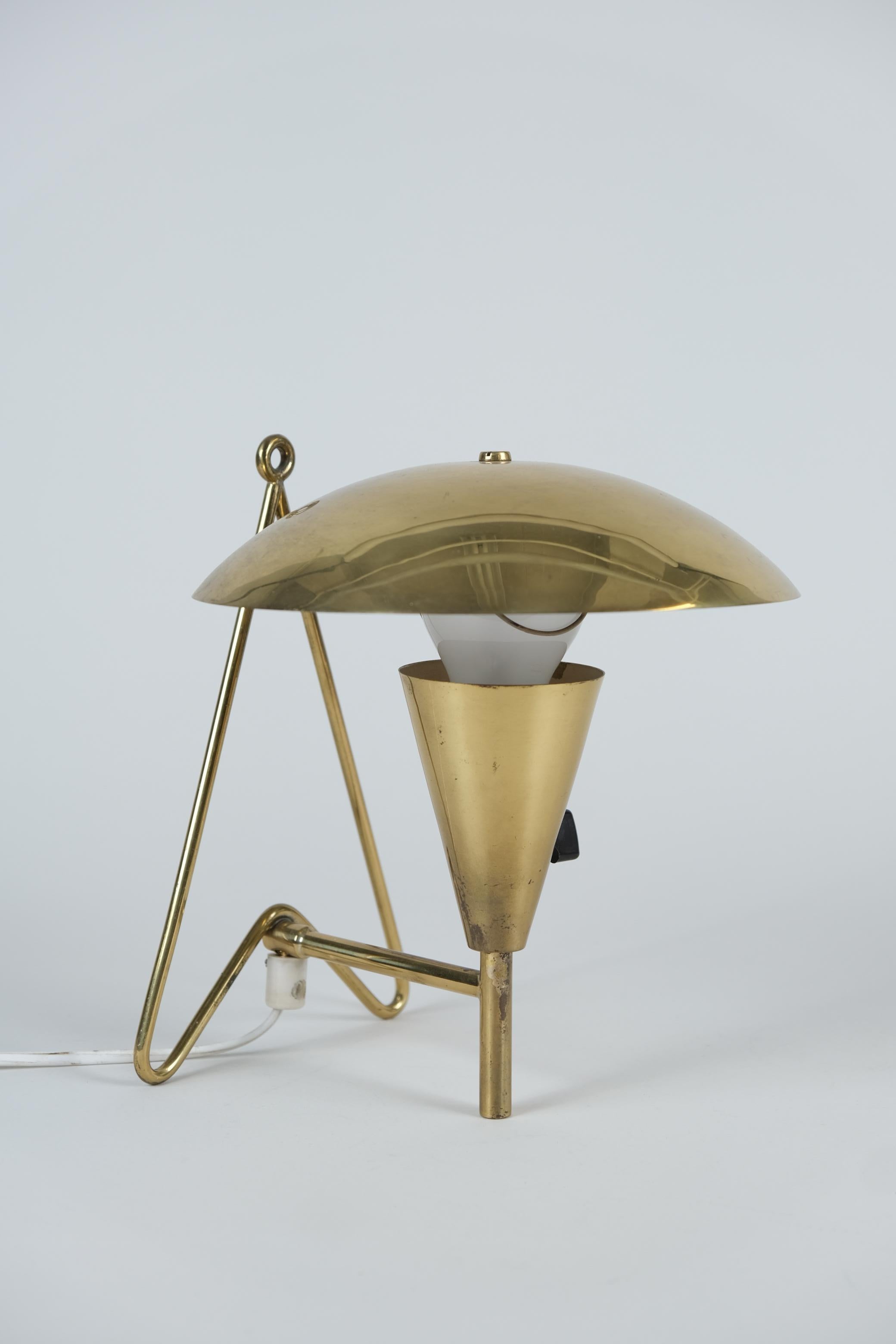 Lámpara de sobremesa/plafón de latón de mediados de siglo fabricada por Itsu en Finlandia en la década de 1950. La lámpara tiene un diseño distintivo con una pantalla de latón ajustable y una estructura que le permite servir tanto de lámpara de mesa