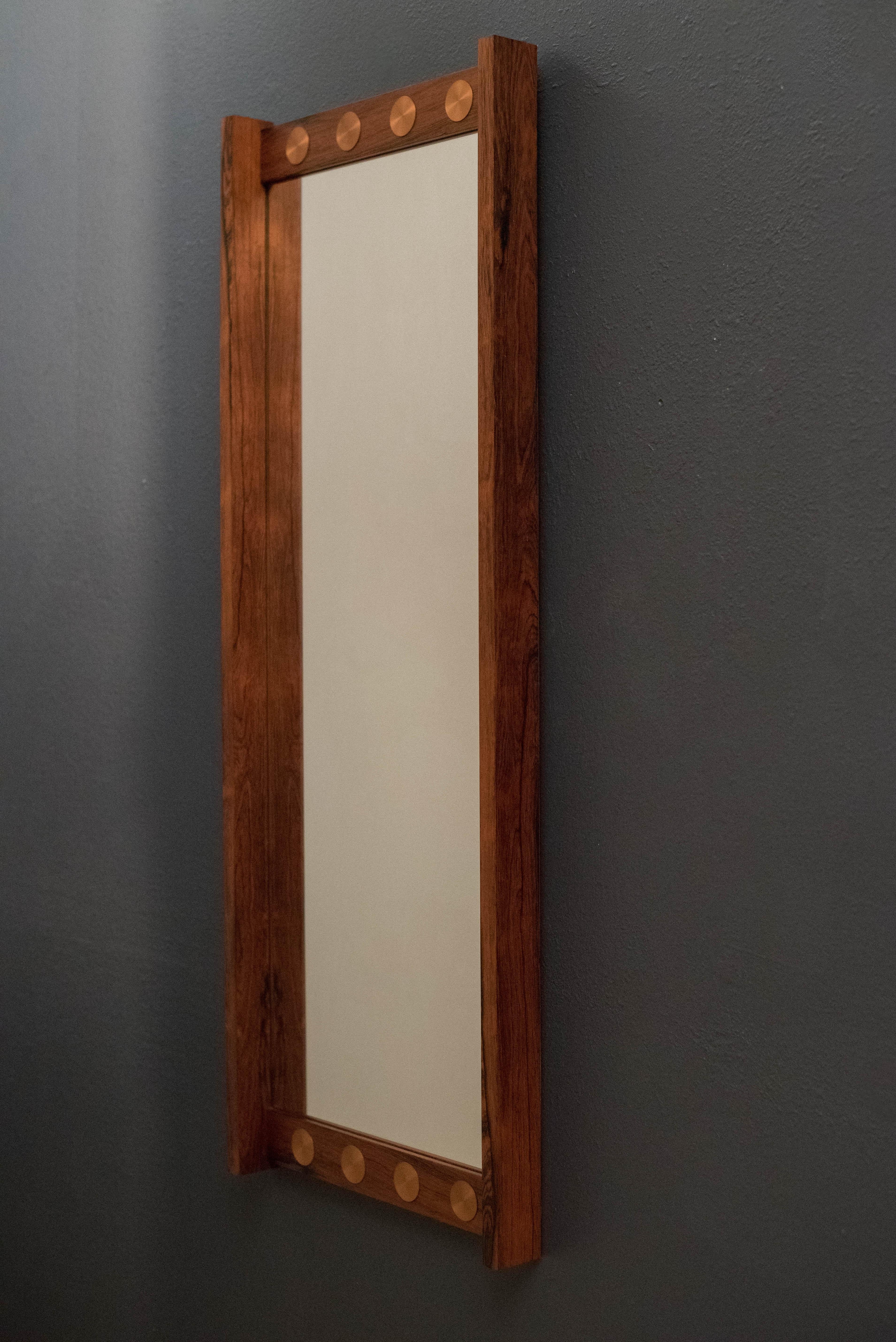 Vintage wall mirror marked G & T, AB Glas and Trä of Sweden. This piece features round copper accents and is framed in rosewood veneer.