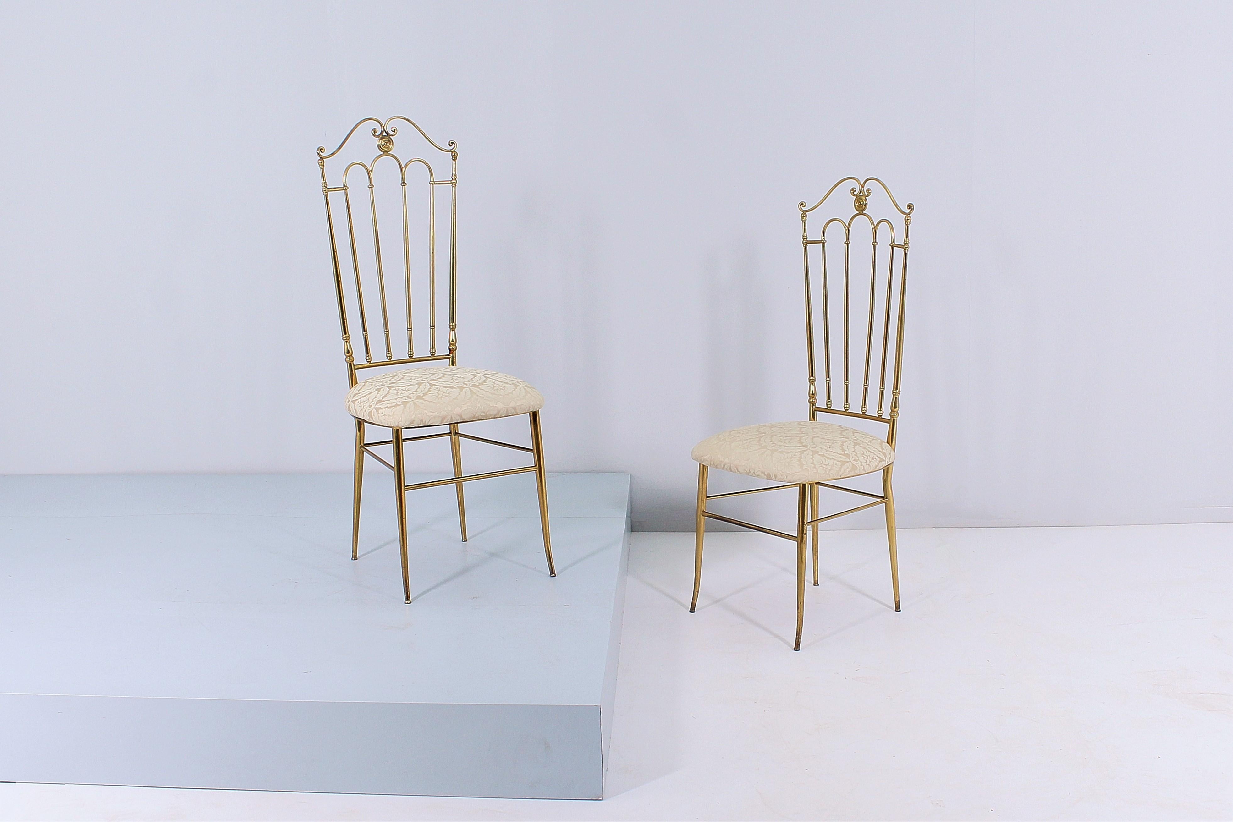 Prestigious pair of dining chairs with high back in gilded brass with seat in beige satin with floral design. Straight lines, curves and decorative elements embellish the design of the entirely brass backs. Attributable to Gaetano Descalzi,