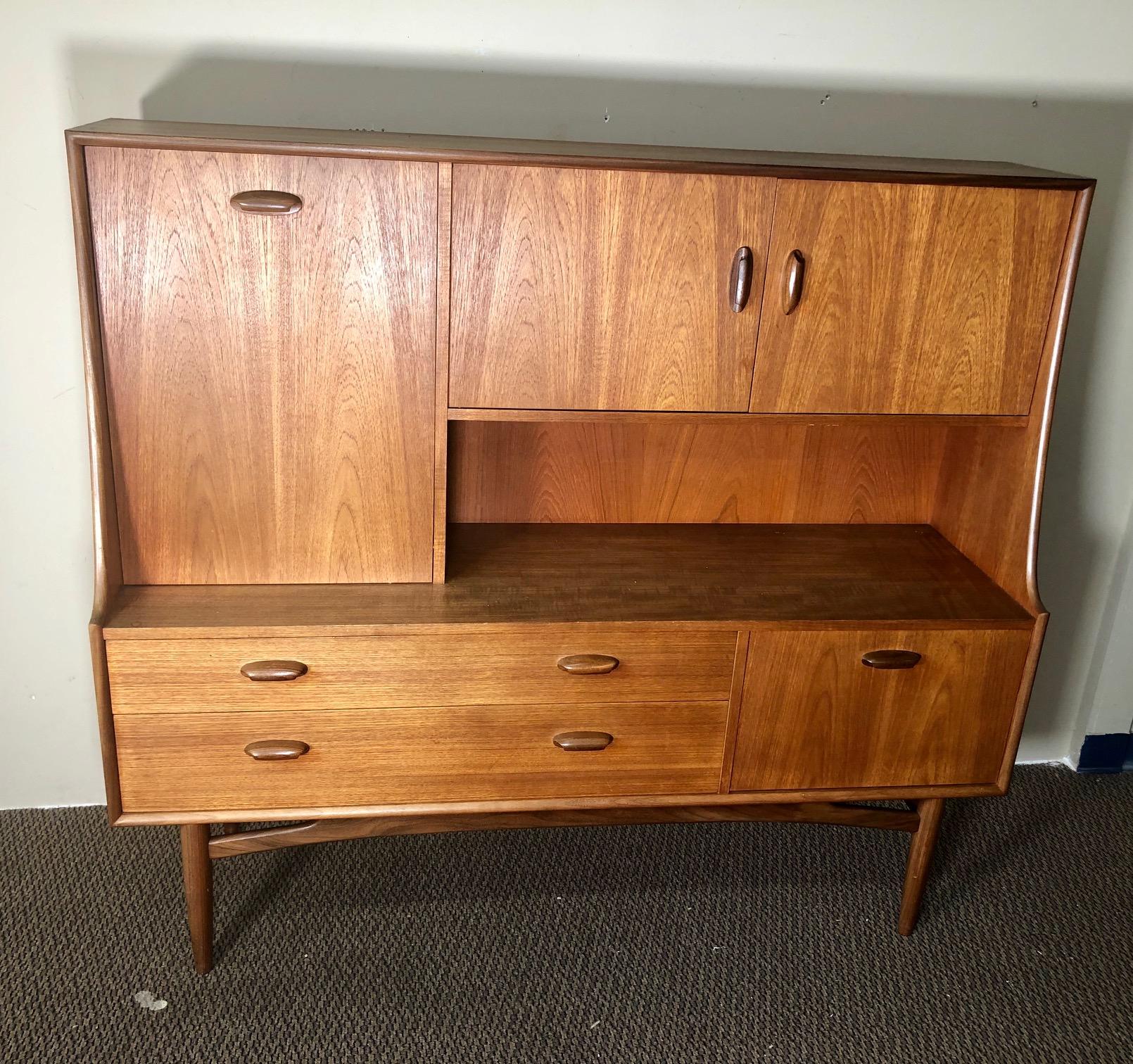 Mid-Century Modern versatile teak highboard by G Plan. Featuring an upper large drop down cabinet that can be used as a small desk and lower drop down cabinet or bar.

Very good vintage condition. There are some marks on the top as shown in