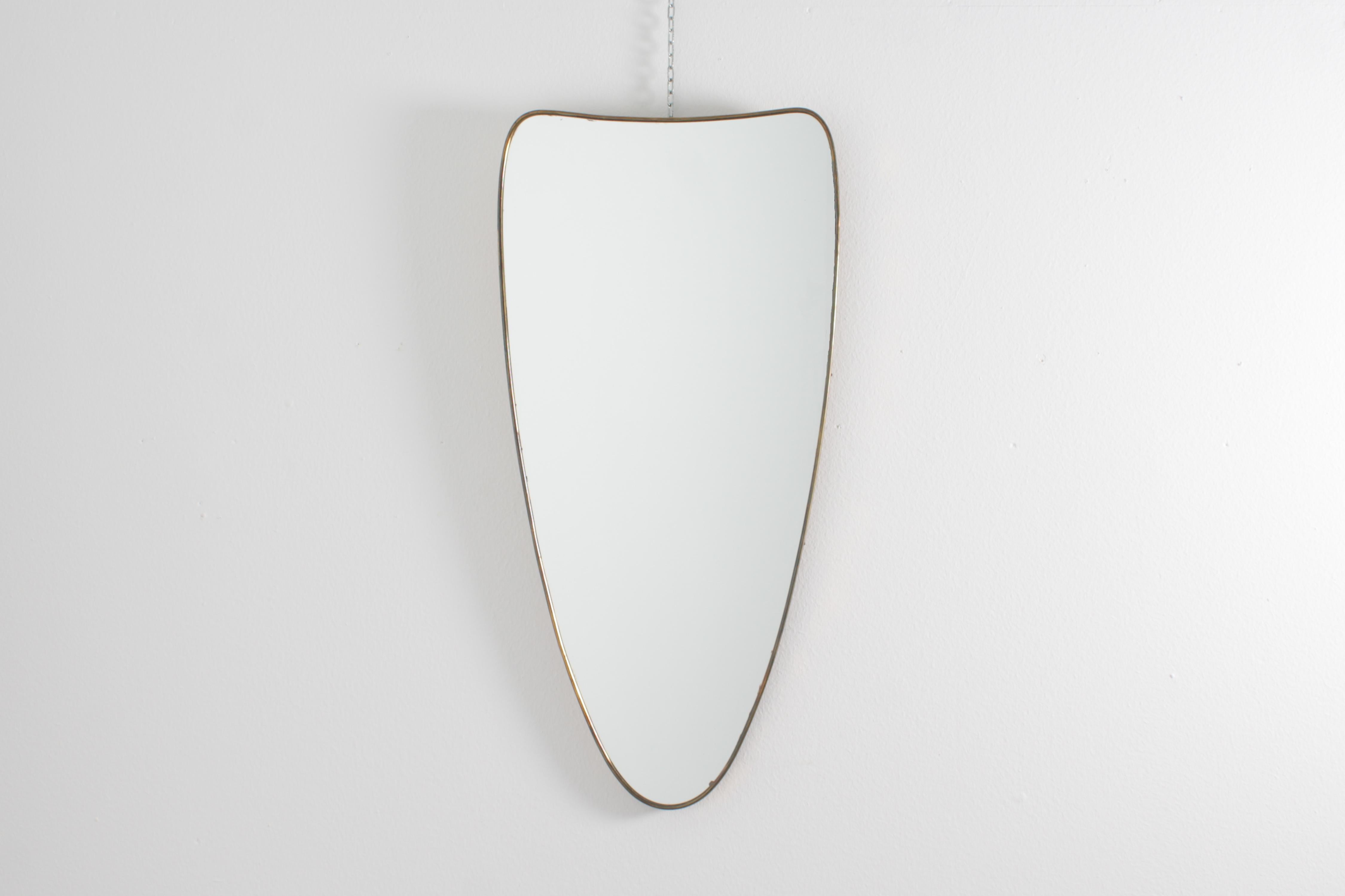 Stylish shield-shaped wall mirror, with narrow frame in golden brass. Valuable Italian production from the 1950s in the style of Giò Ponti.
Wear consistent with age and use.