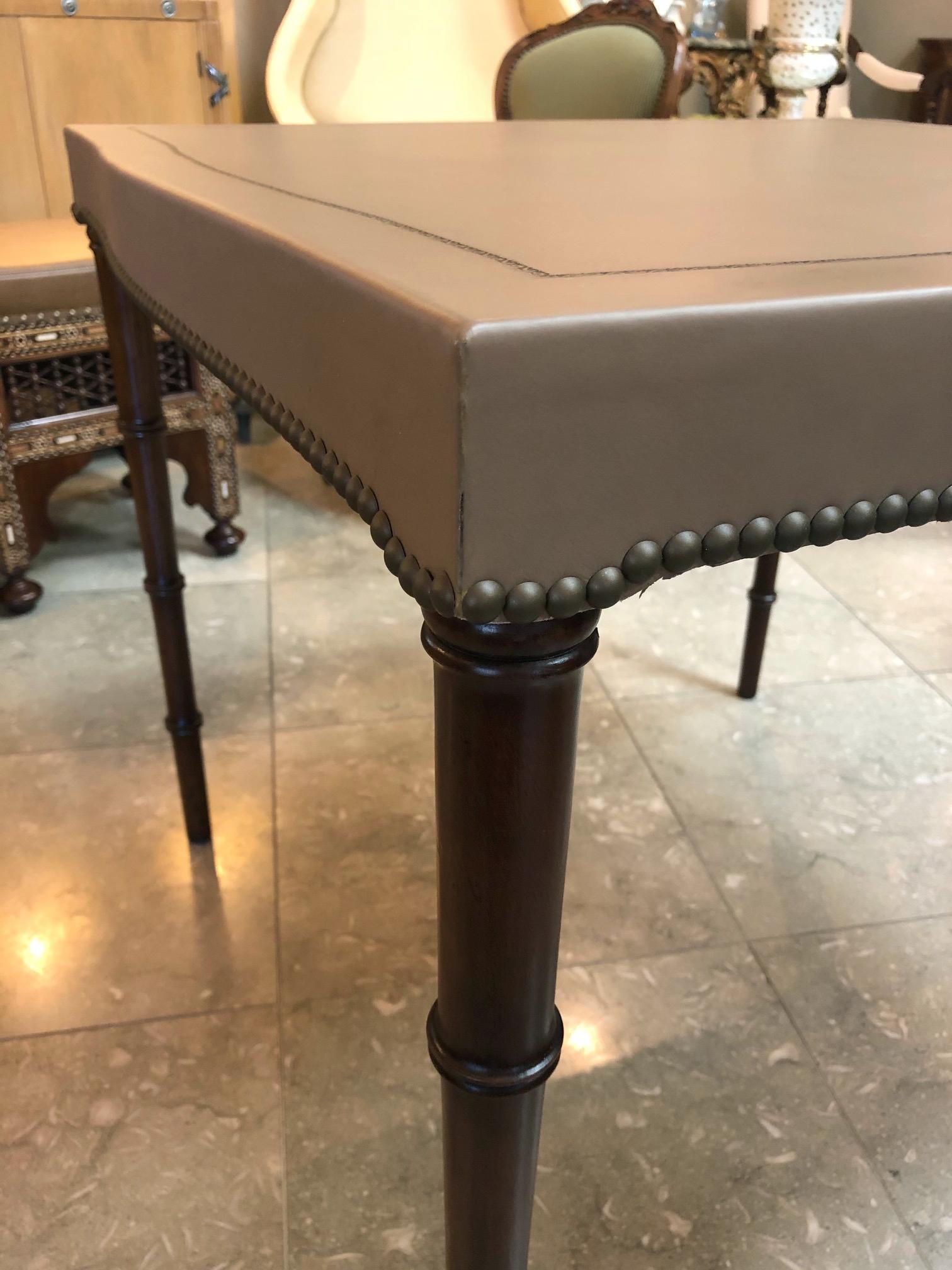 The square table with serpentine sides adorned with black hand-tooled perimeter border; raised on faux bamboo supports; Barnard and Simonds Co. (1898-1967), Rochester, NY, moving to Grand Rapids, MI in 1959; purchased by Baker Furniture in 1967.