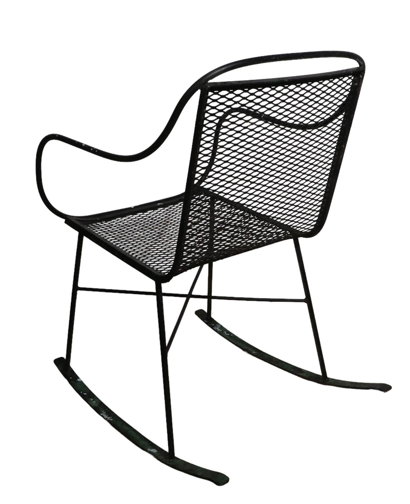 Stylish architectural mid century wrought iron and metal mesh rocking chair attributed to Salterini. Good, clean, original, ready to use condition, showing only light cosmetic wear, normal and consistent with age. 
 Total H 33 x Arm H 26.5 x Seat H