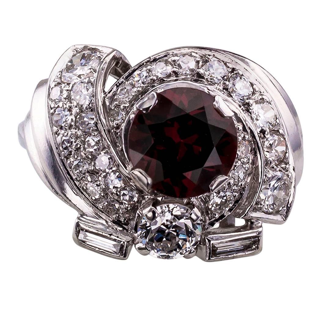 1950s mid century garnet and diamond platinum cluster ring.  The cluster design centers upon a vibrant round-cut red garnet, framed by an array of twenty-five diamonds totaling approximately 1.00 carat, approximately  H - J color and VS - SI