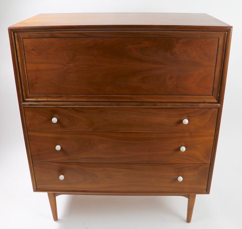 Classic midcentury Highboy chest designed by Kipp Stewart and Stewart McDougall from the Declaration Line. The cabinet features a drop, or fall front panel on top which, when opened revel two slide out drawers, over three full size drawers. This