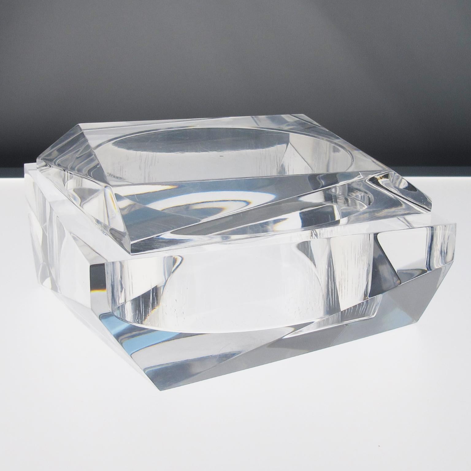 This stunning geometric Lucite decorative trinket-lidded box, made in the 1960s, features a modernist shape with an incredible carved prismatic design. The box is made of crystal clear Lucite or Plexiglass with a thick material. It is marked