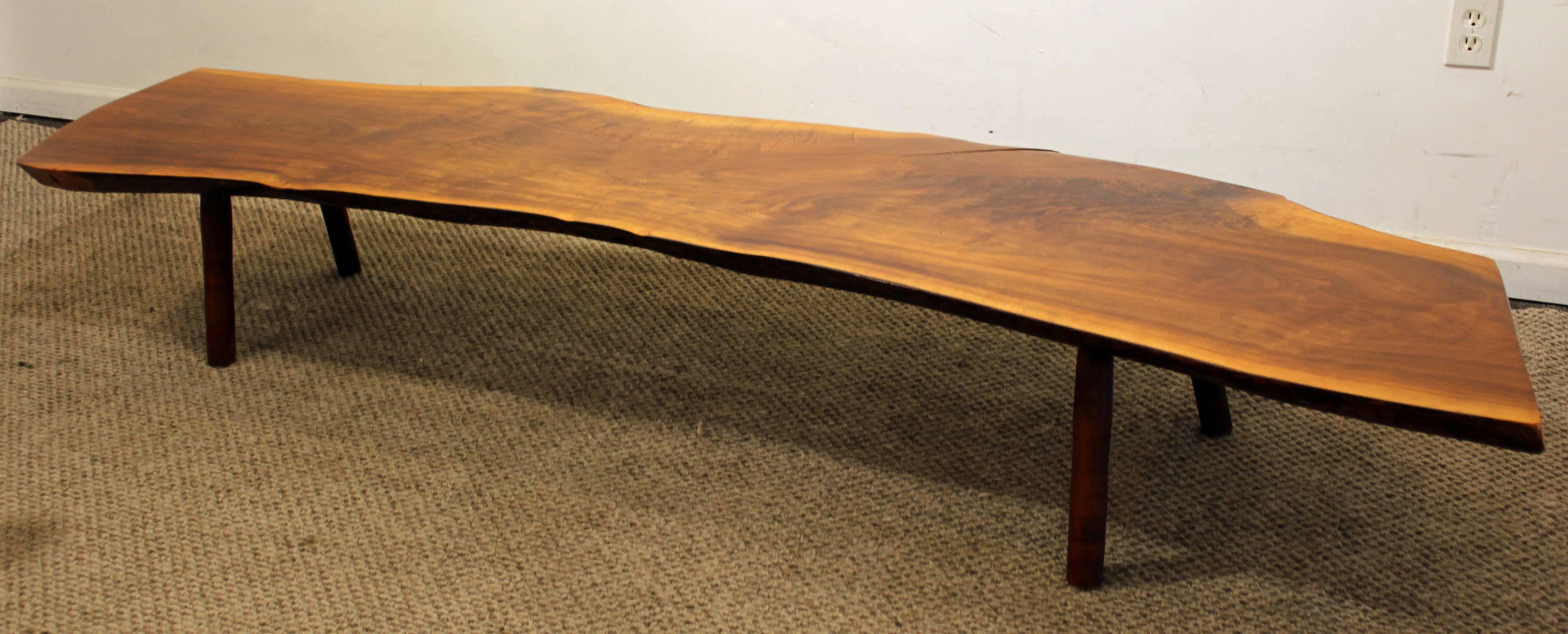 Offered is a live-edge walnut slab coffee table, similar to the style of Nakashima. It has a solid wood walnut slab with a finished top and sides on four wooden legs. It was made in a New Hope art studio in the 1970's.