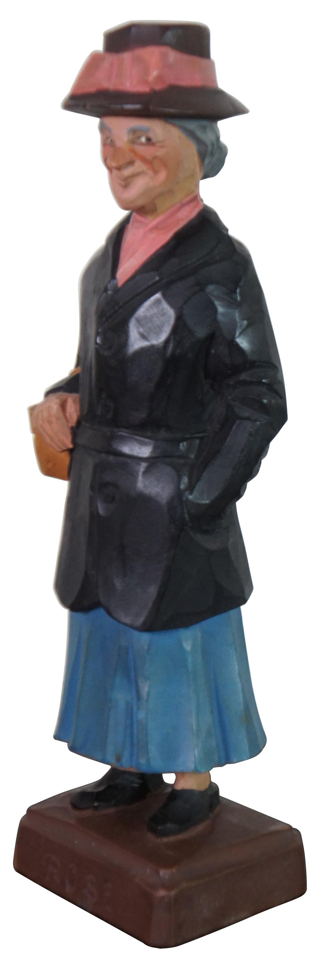 Mid century carved wood folk art figure by Gerald Pat Hannah, titled “Rose,” showing an old woman in a dark hat and coat with a purse on her arm. “One of the original three Hannah brothers (Charles, Pat and Tom) who became wood carvers in the 1930’s
