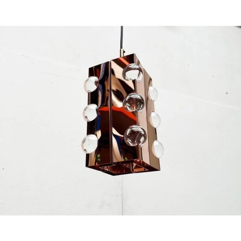 Imponente lampada a sospensione in rame Cosack.

Questa lampada convince per la sua matericità e per i complessi riflessi ed effetti luminosi che ne derivano. Il rame lucido e il vetro acrilico trasparente si riflettono e sono dotati di connessioni