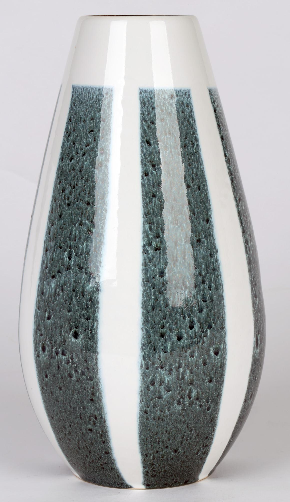 Un vase en céramique ouest-allemand très élégant, décoré de panneaux bleus mouchetés sur un fond blanc, datant d'environ 1960. Le vase a une forme de larme haute, simple et élégante et est décoré de glaçures blanches brillantes avec six longs