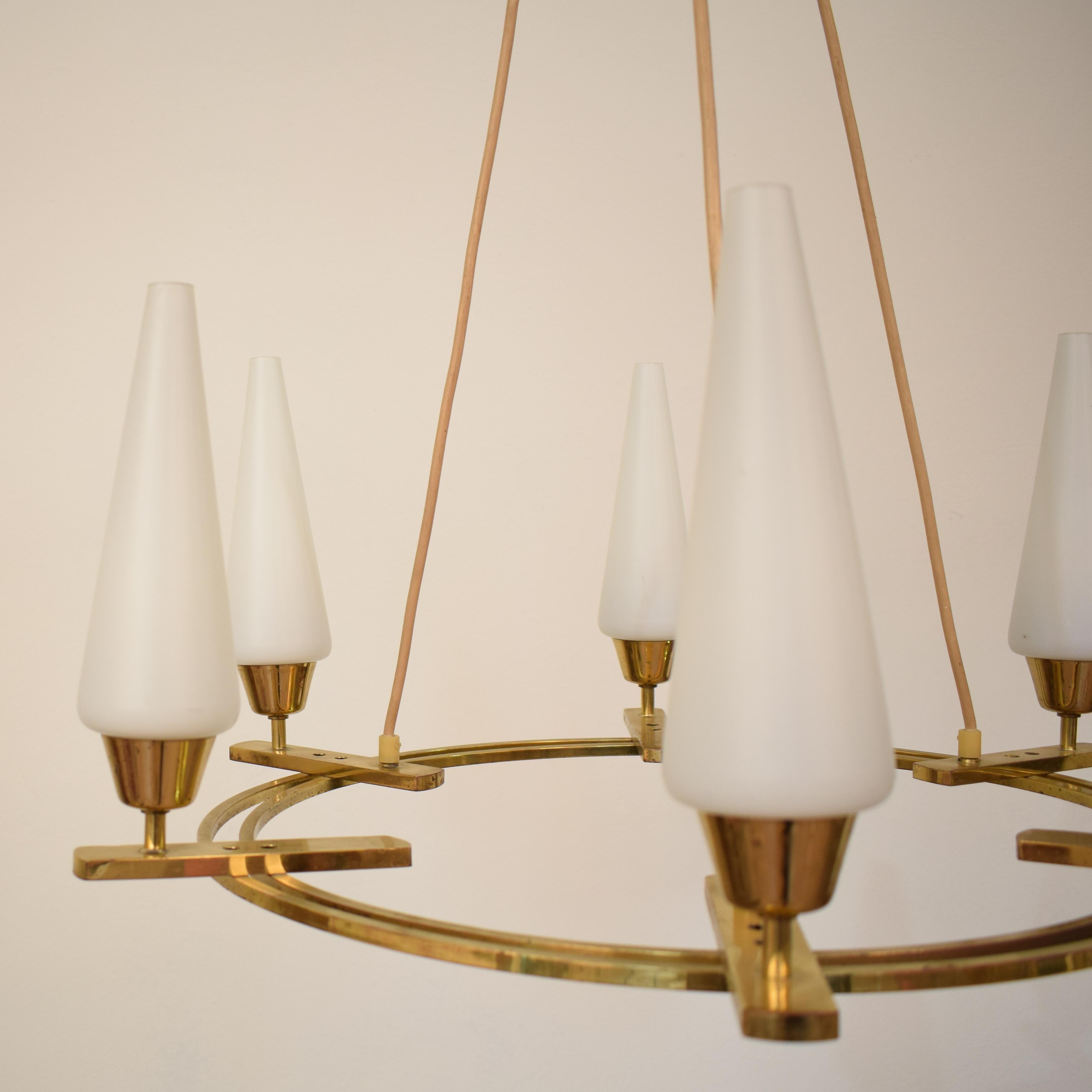 This beautiful and elegant midcentury brass chandelier was produced by Vereinigte Werkstätten München in the 1970s.
It has six arms with opaline glass. The structure is out of brass and shows some great details and Patina.
The chandelier is in