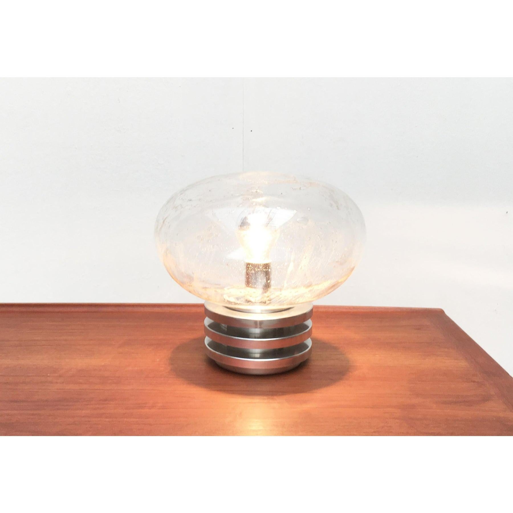 Esta lámpara de mesa Bulbo de mediados de siglo fue producida por el fabricante alemán Doria Leuchten. Viene con un gran difusor de cristal y una base laminar. El cristal estructurado crea un juego de luces especial en la habitación. Esta pieza