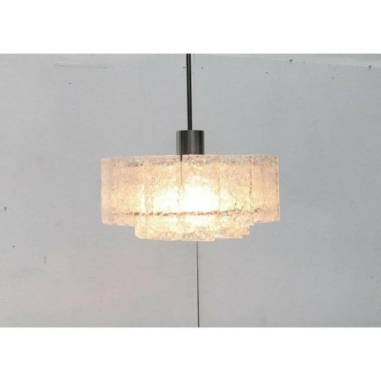 Imponente candeliere del rinomato produttore Doria Leuchten.

Gli elementi di vetro strutturale si rompono e potenziano la luce della lampada all'interno. Questo li rende una lampada funzionale e un oggetto luminoso in uno. Gli elementi in vetro