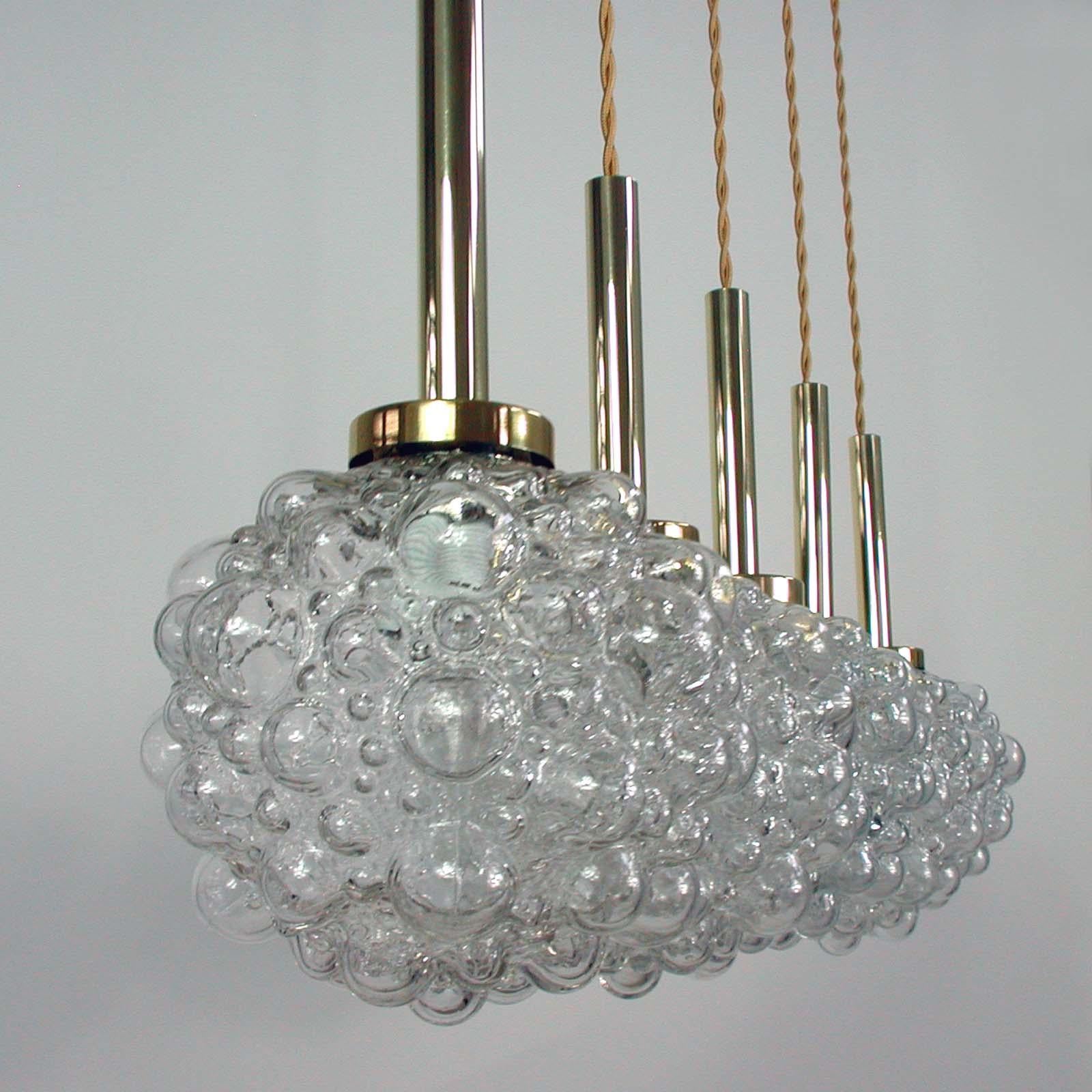 This Space Age pendant lamp was designed and manufactured in Germany in the 1960s. It is made of clear bubble glass and has got a brass top. The lamp has been rewired with new gold colored fabric cord (39.4