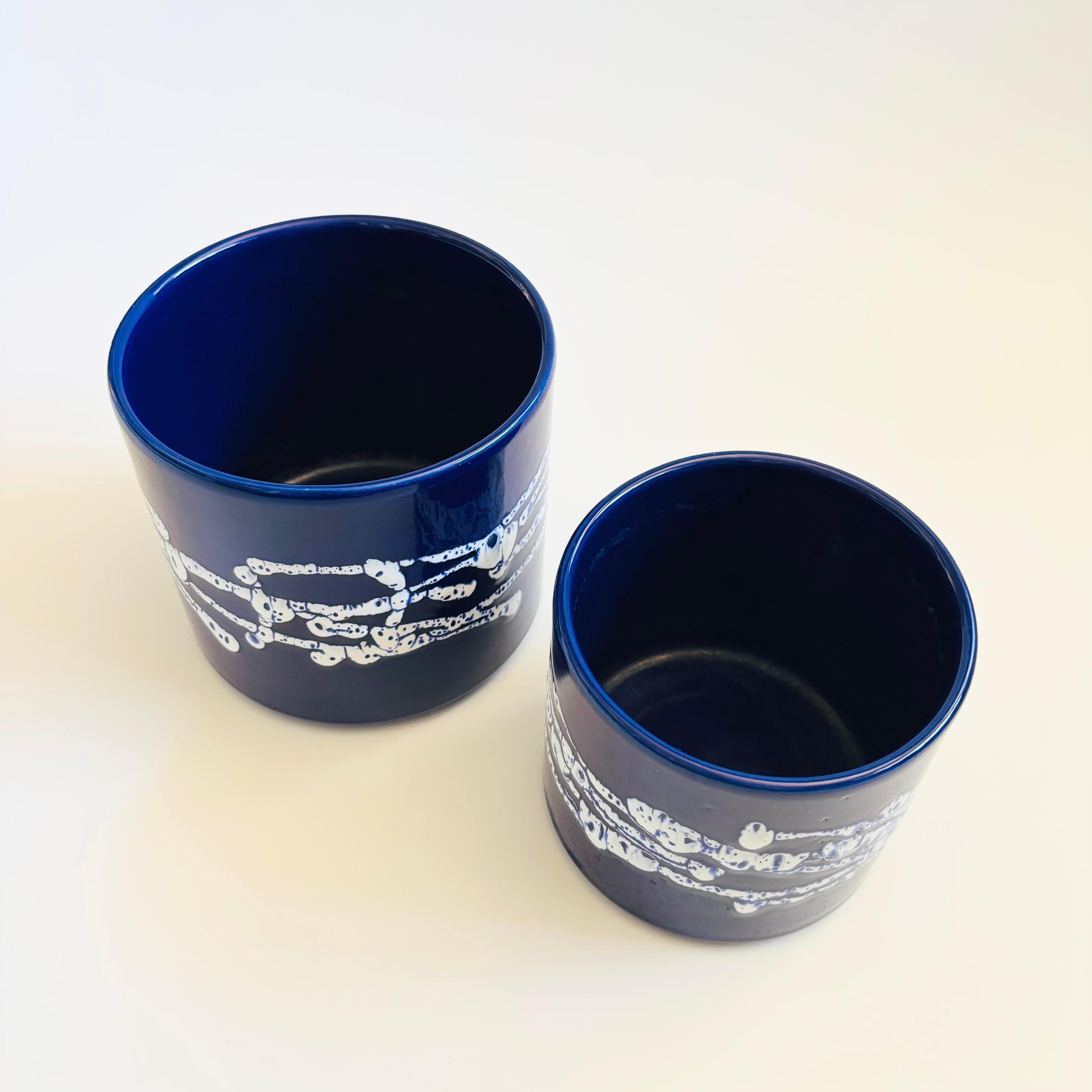 A set of 2 mid century vintage ceramic planters in 2 sizes. Modern cylinder shape. Dark blue glaze with a free form white design around the sides. Marked Germany on the bases.
Measurements:
6