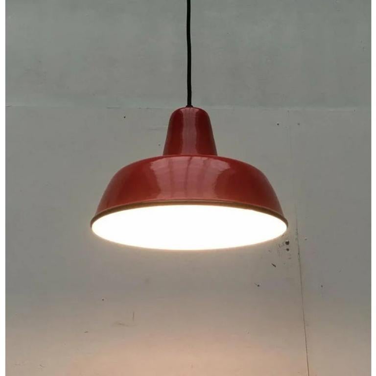 Semplice lampada a sospensione smaltata in un colore speciale.

Pendolo funzionale nella classica forma di una lampada industriale o da officina. L'ombrello è completamente in metallo e smaltato. L'ombrello rosso è interrotto in nero verso il bordo.