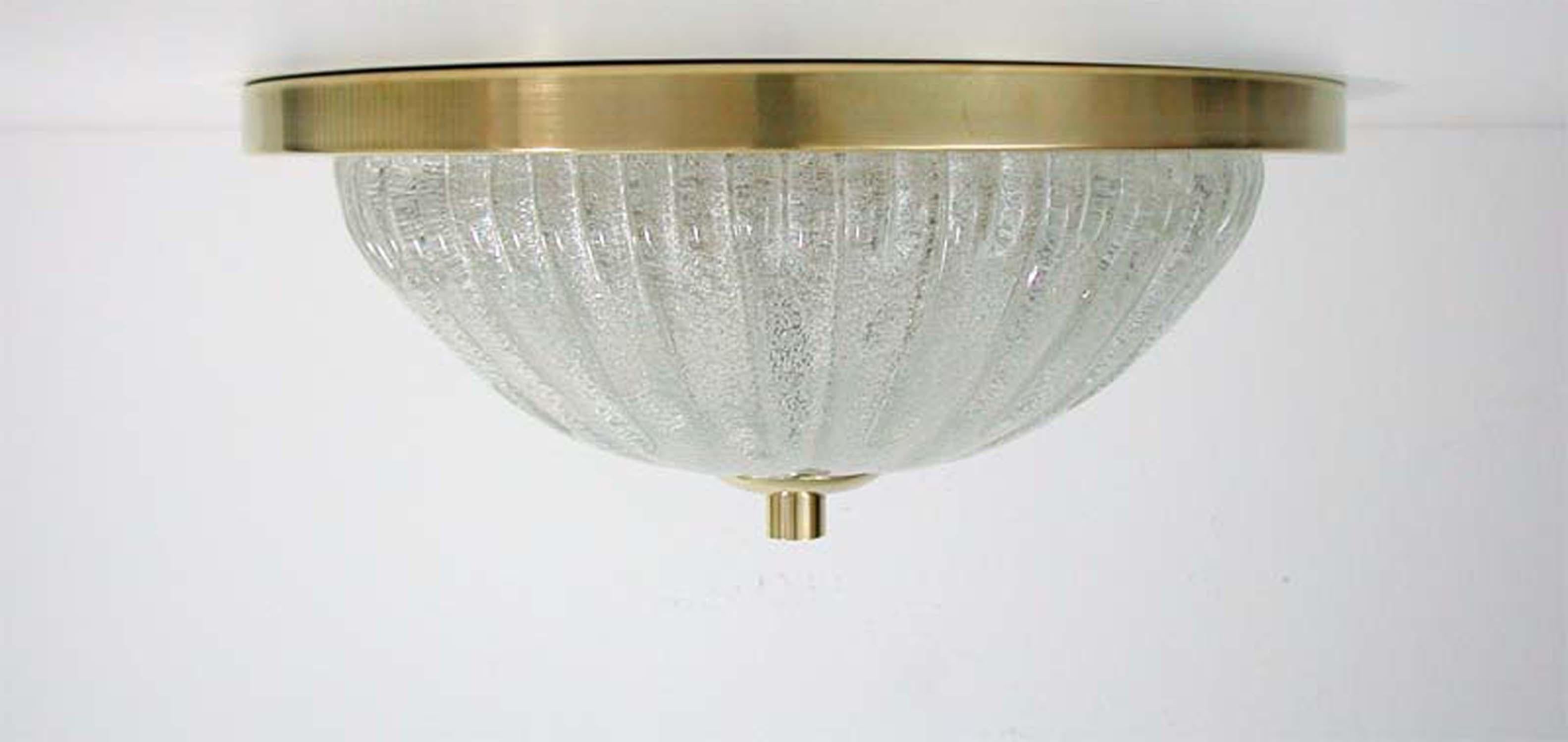 This ice glass and brass flush mount in the manner of Kalmar Franken KG was designed and manufactured in Germany in the 1960s. The lamp can also be used as a wall light / sconce.

The lampshade is made of clear textured glass. The base is polished