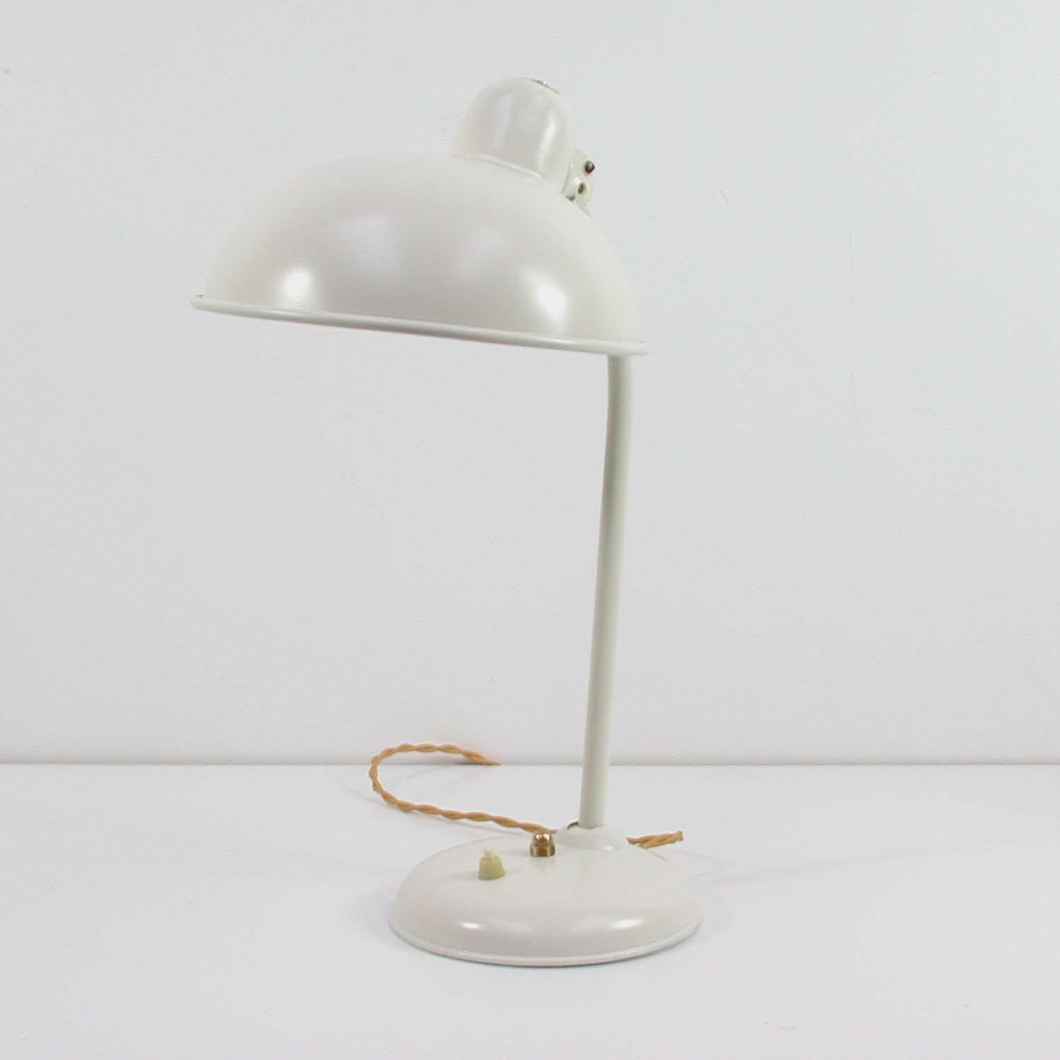 This cream colored vintage industrial desk lamp was manufactured in Germany in the 1940s-1950s by Helo Leuchten. 

It features an adjustable lamp arm and lampshade. The light is fully working and has been rewired with a gilt fabric cord for use in