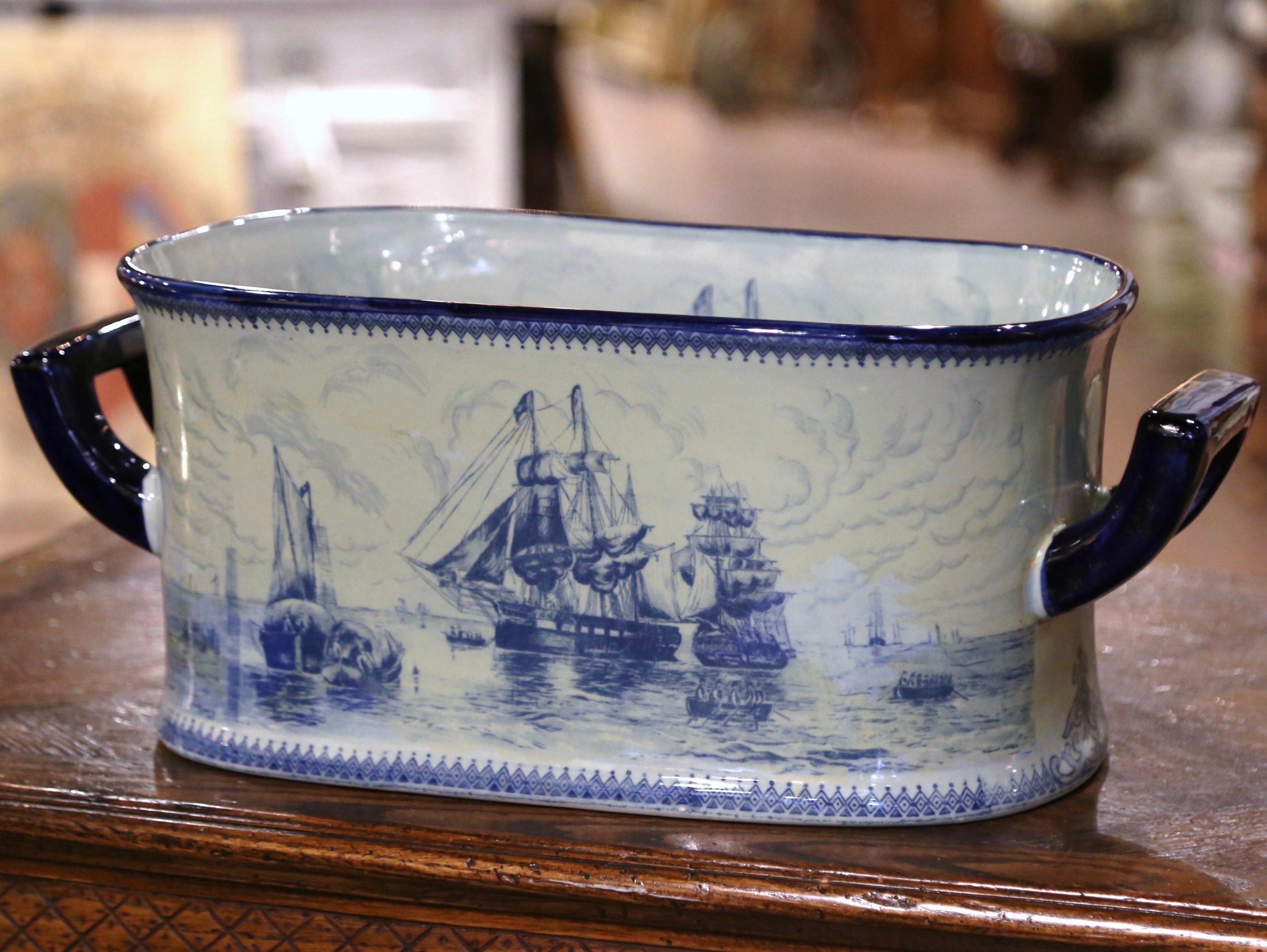 This large antique planter was crafted by Meissen in Germany circa 1960. Oblong in shape, the blue and white faience jardinière is dressed with hefty blue handles and features hand-painted marine scenes in the Delft manner, with large sailing ships,