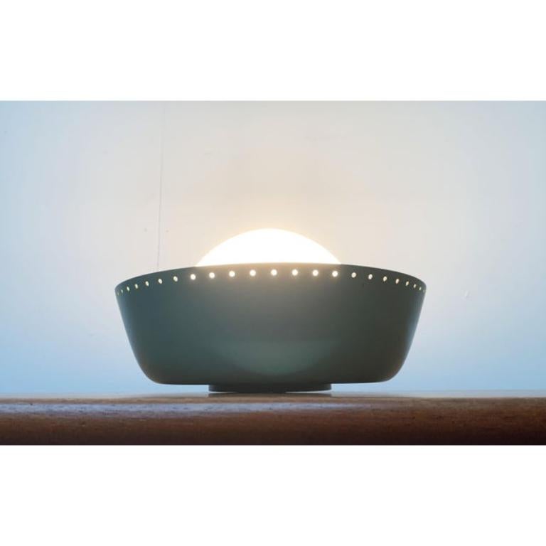 Lámpara de techo Mid Century de Bega.

Un diseño sobrio en un lenguaje minimalista de la forma. El difusor de cristal opalino se asienta en el centro de una pantalla metálica. La pantalla está lacada por fuera en un tono verde con textura