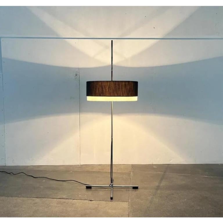 Lampada da terra minimalista di metà secolo.

Il dettaglio speciale di questa lampada è la semplice base a stella, composta da aste quadrate. Questi finiscono in elementi di legno. Le barre quadrate della base si ritrovano anche nel fusto della