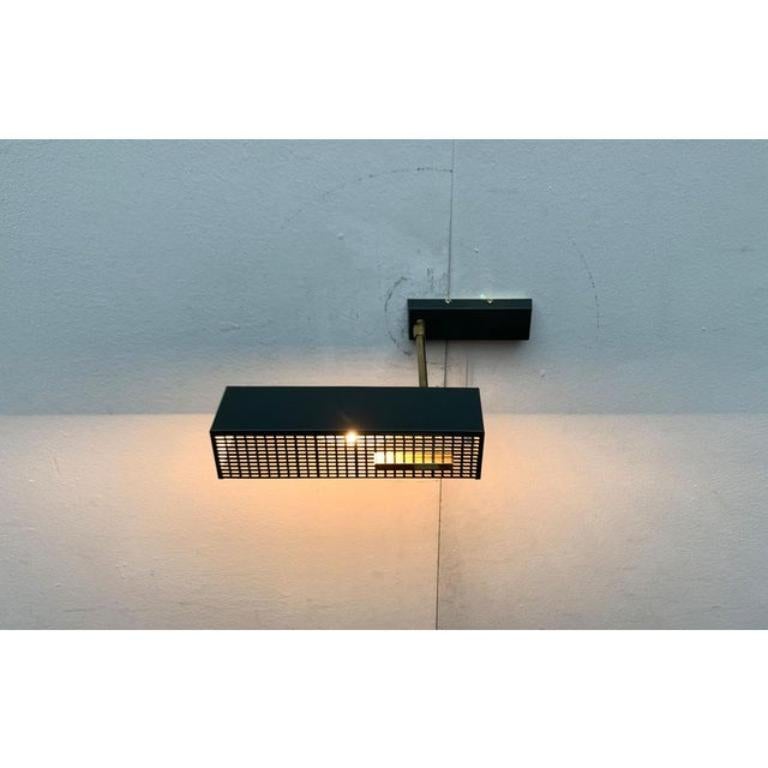 Lampada da parete di metà secolo con ombrello flessibile. Probabilmente da Imperatore.

Un design minimalista. Le forme cubiche percorrono questo design, dallo schermo alla placca a muro. Il dettaglio più evidente è la sottile perforazione della