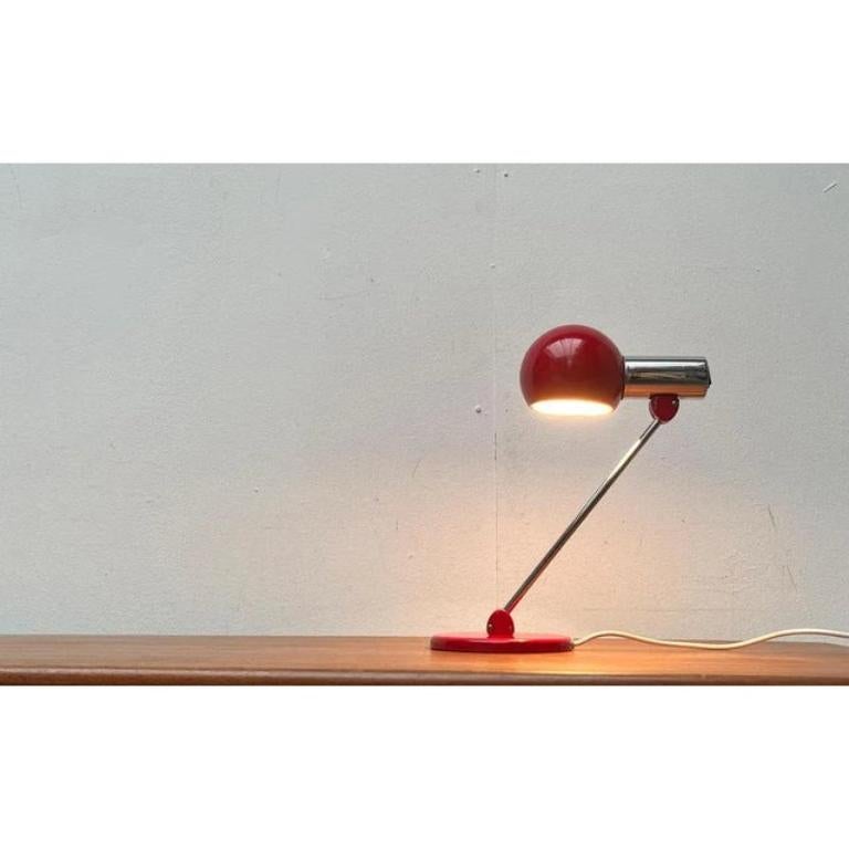 Rare table lamps from Kaiser Leuchten.

A minimalist design of high functionality. The light head consists of a chrome cylinder that is connected to the chrome -plated shaft via a ball joint. The slim shaft ends with another joint in a simple, red