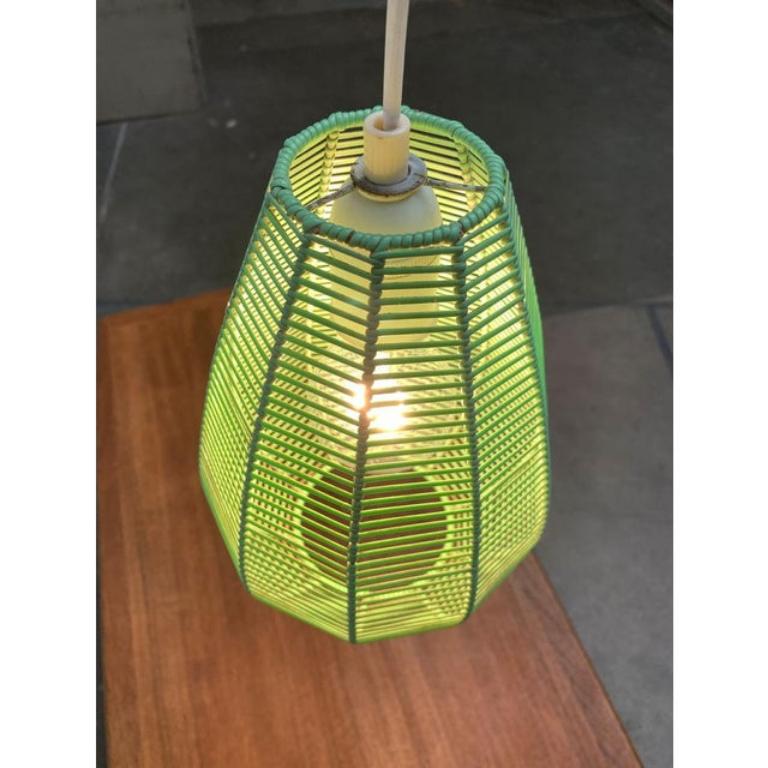 Small Mid Century pendant light with striking fabric.

The luminaire screen consists of a wire body, which is covered with a light green plastic cord. The dense tissue shields the bulbs in a limited extent. At the same time it throws a striking